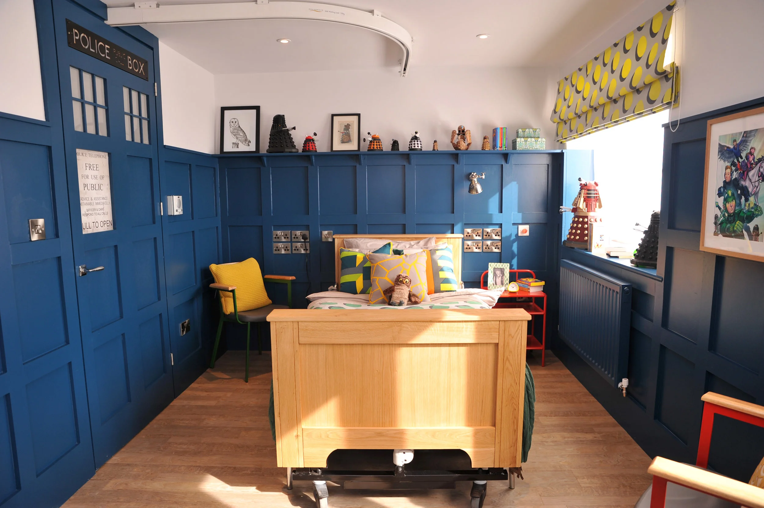 Blue Doctor Who themed bedroom with a ceiling track hoist and hospital bed