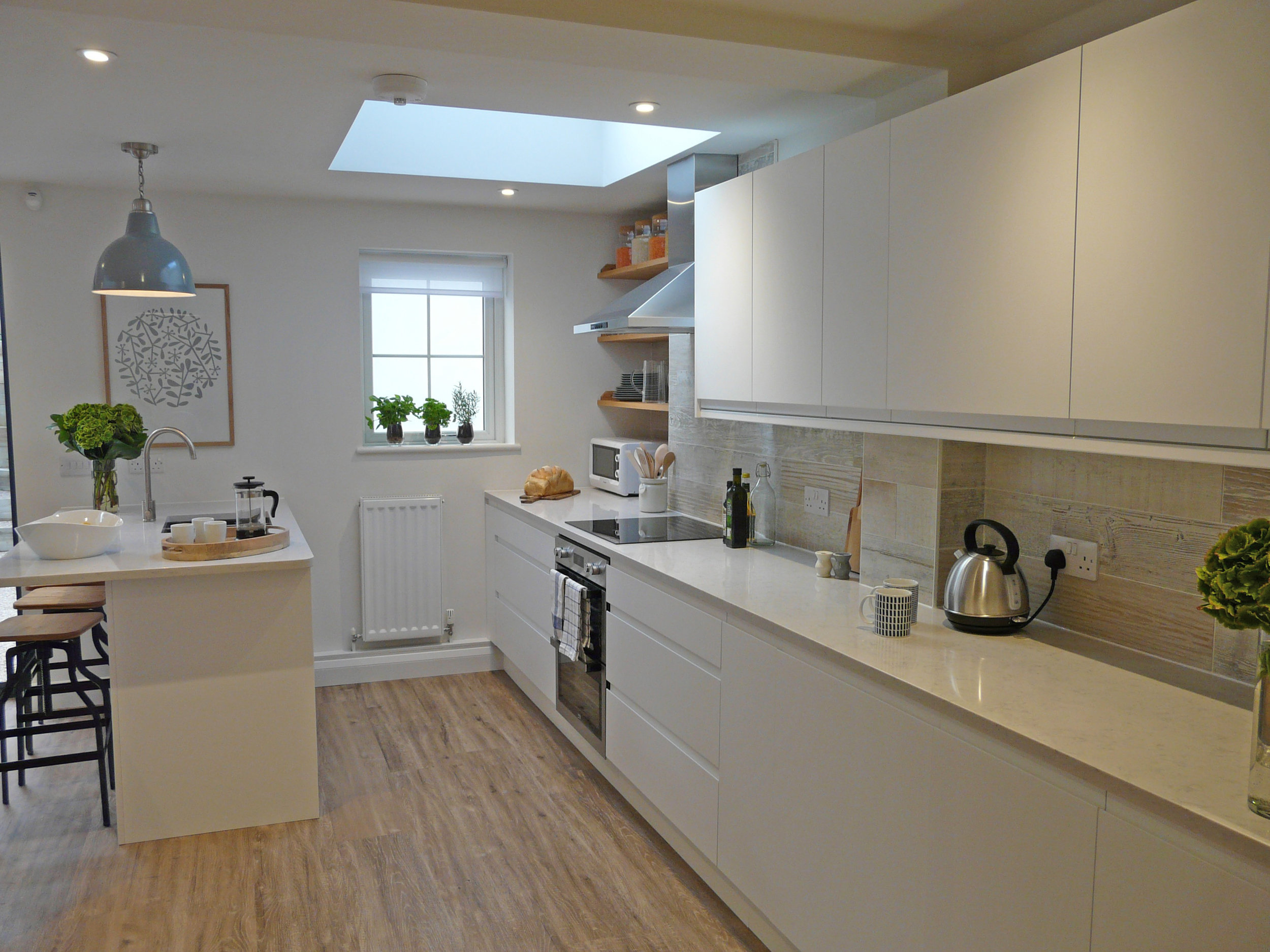 White gloss handleless kitchen with timber tiled splash back.