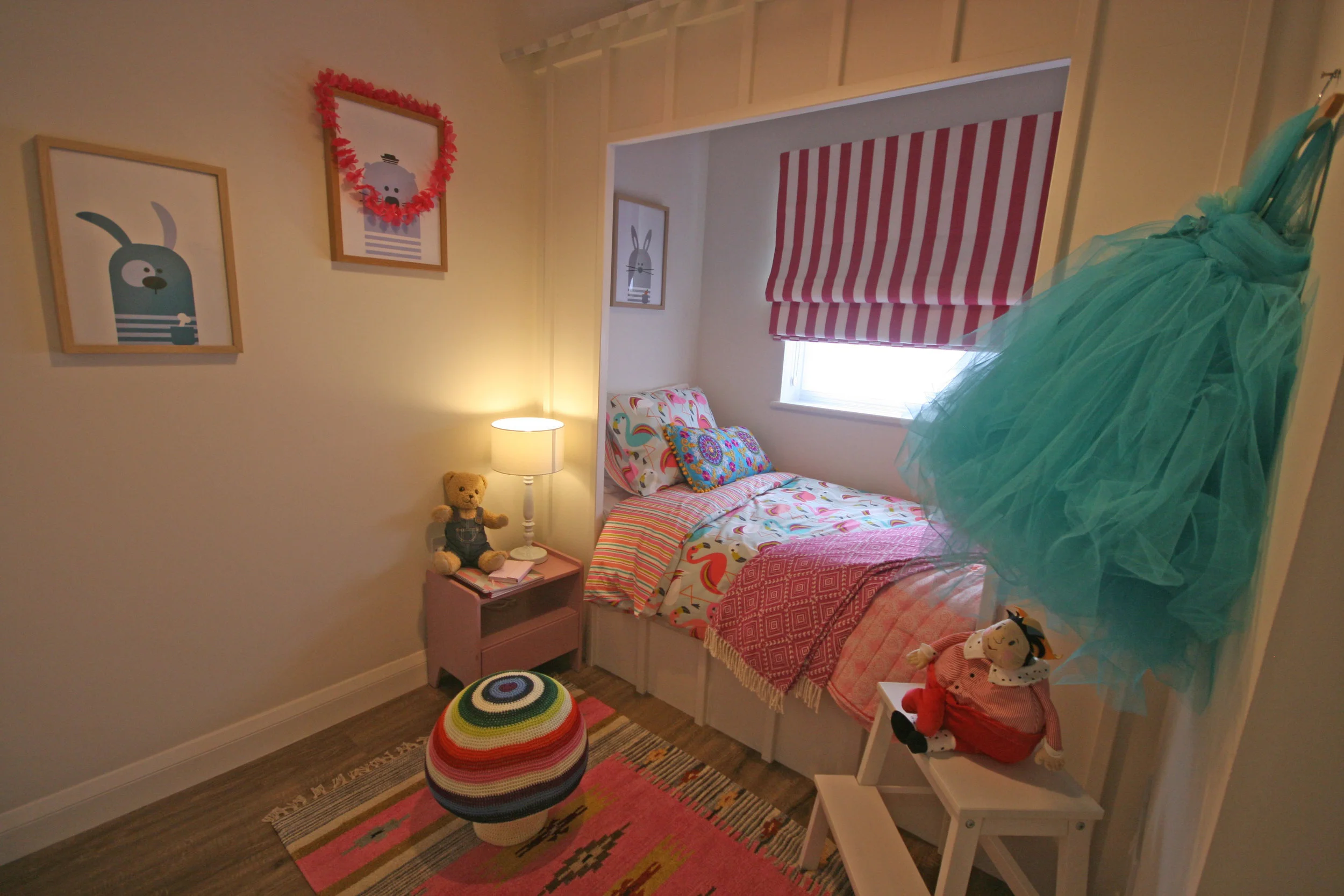 Bespoke white cabin bed designed in the shape of a house with pink accents around the room