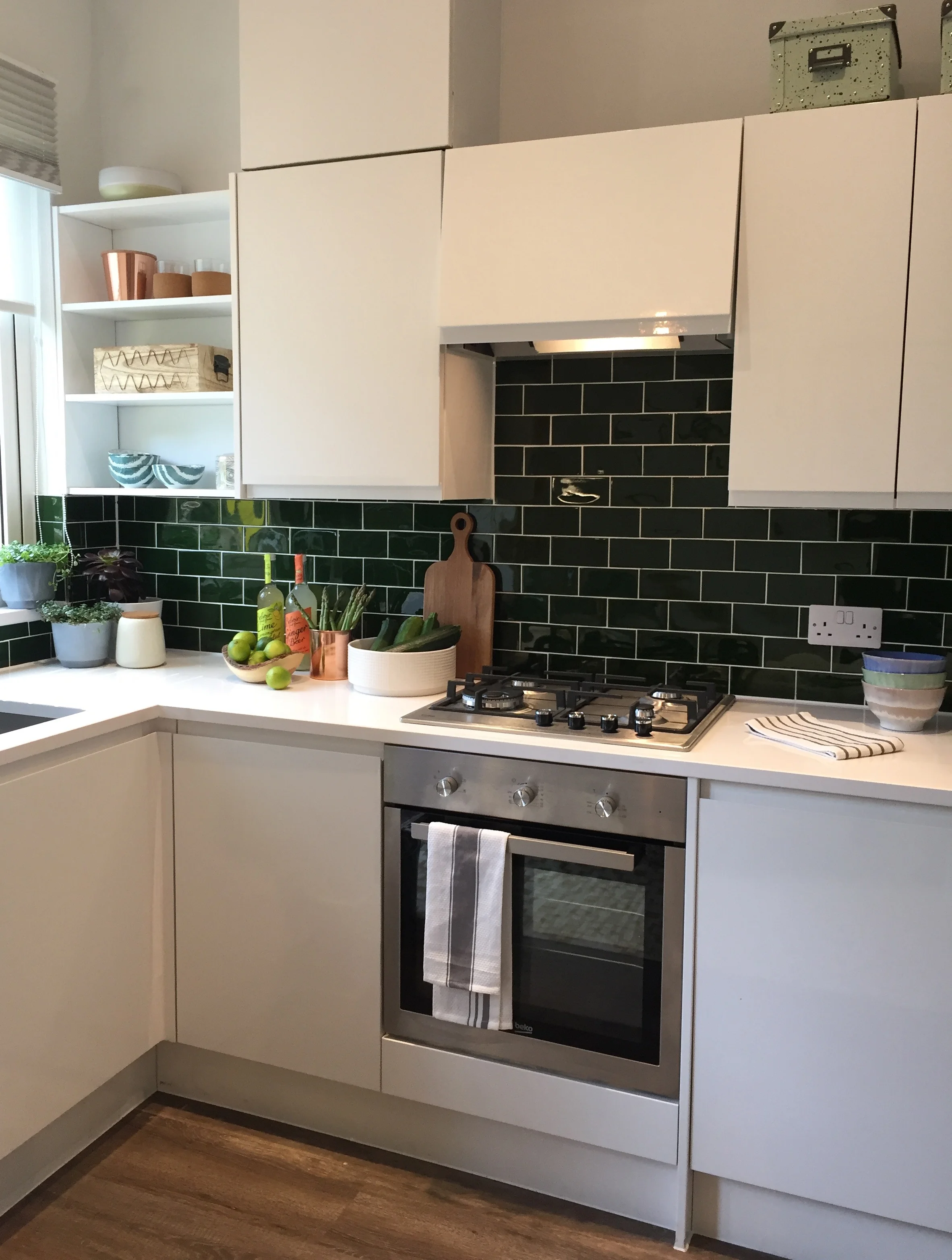 White gloss handleless kitchen with bottle green metro tiles