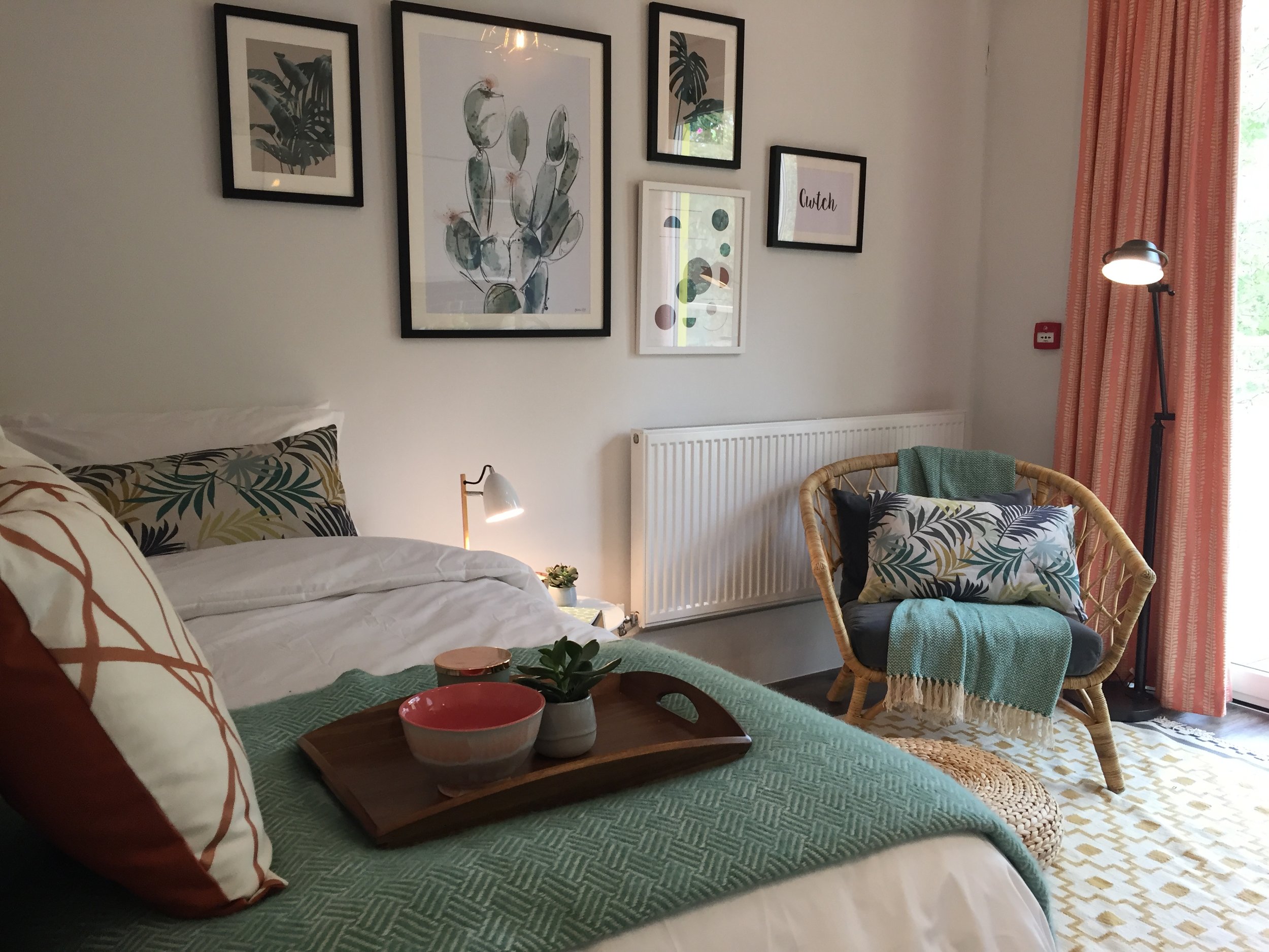 Botanical bedroom with coral curtains and rattan chair.