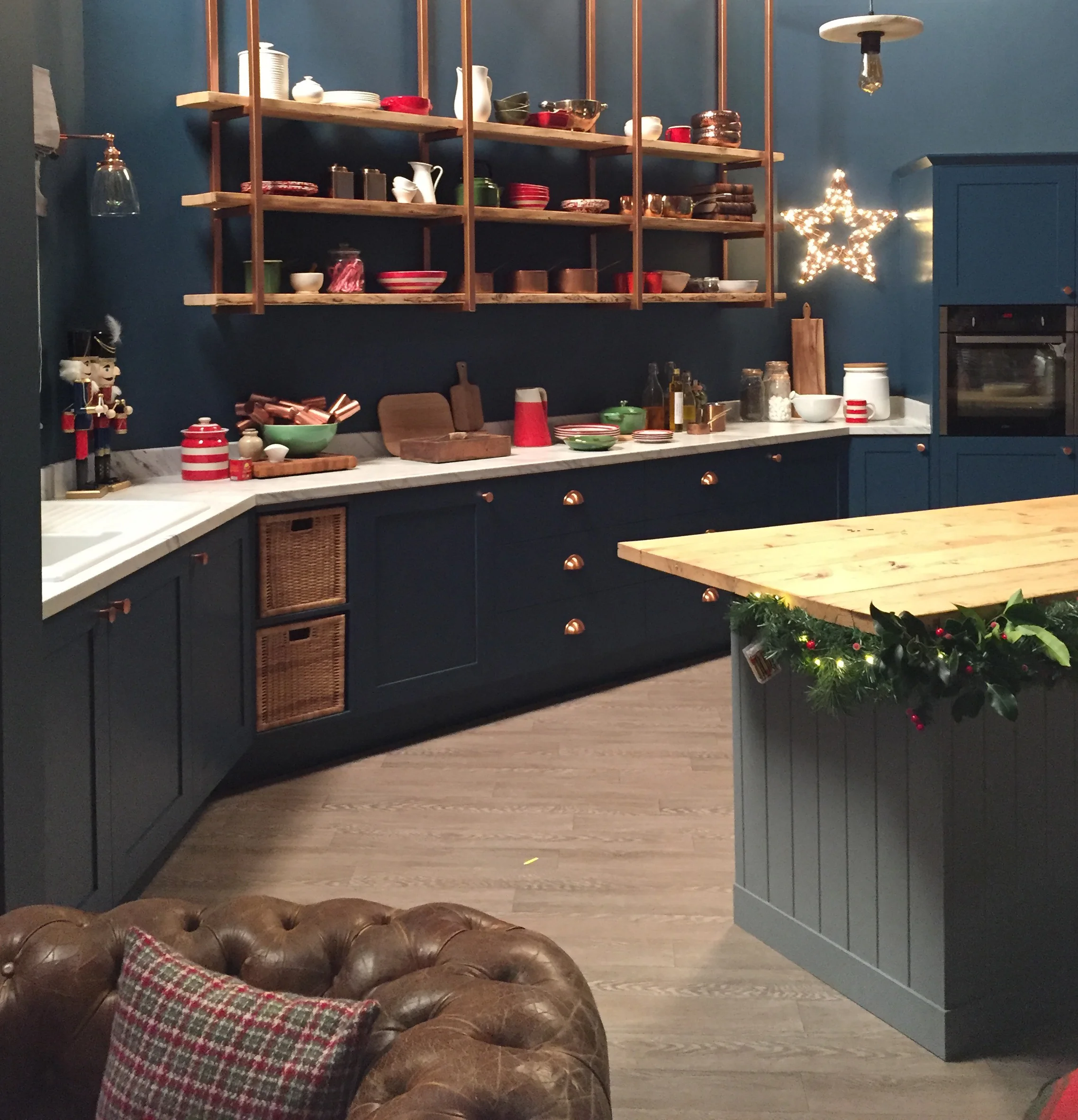 Navy kitchen with copper shelving brackets and handles.