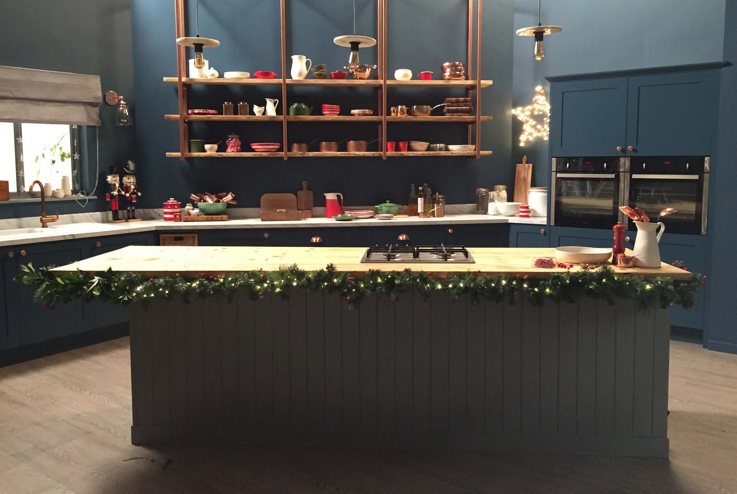 Navy kitchen with grey island in the front with christmas garlands around it.