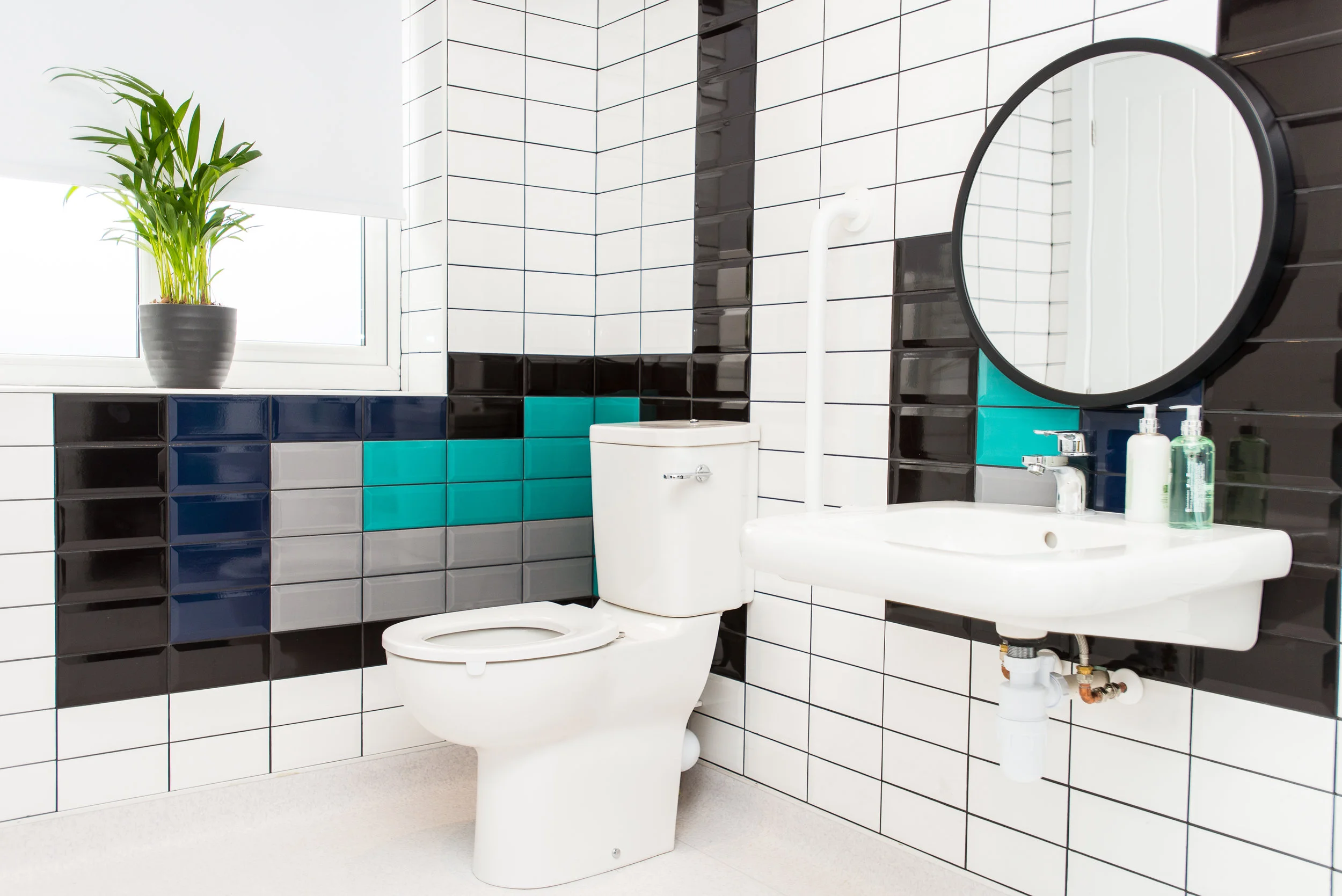 Disabled accessible wet room with black, navy, white, grey and turquoise tiles