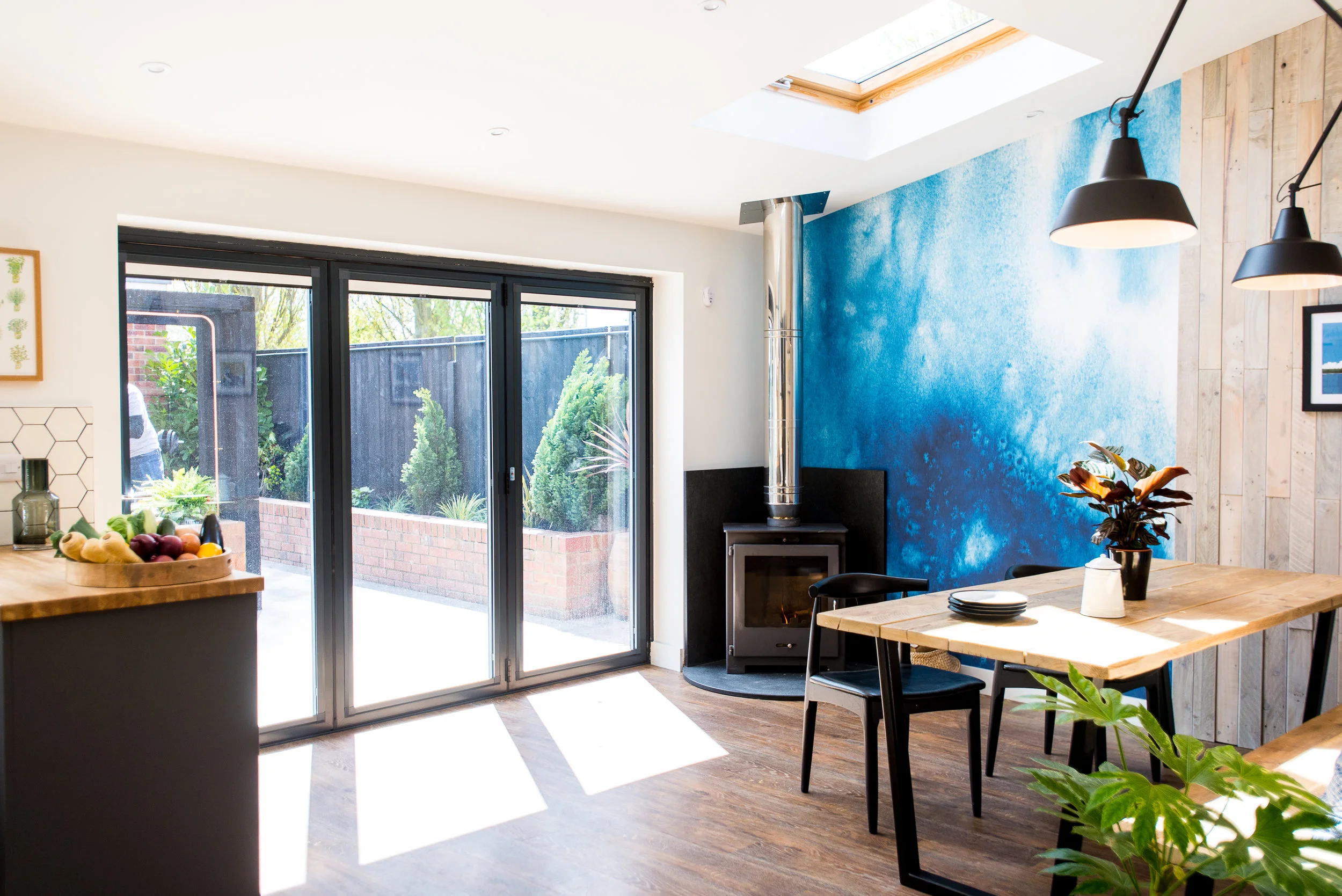 Bright dining space with bifold doors and blue wallpaper