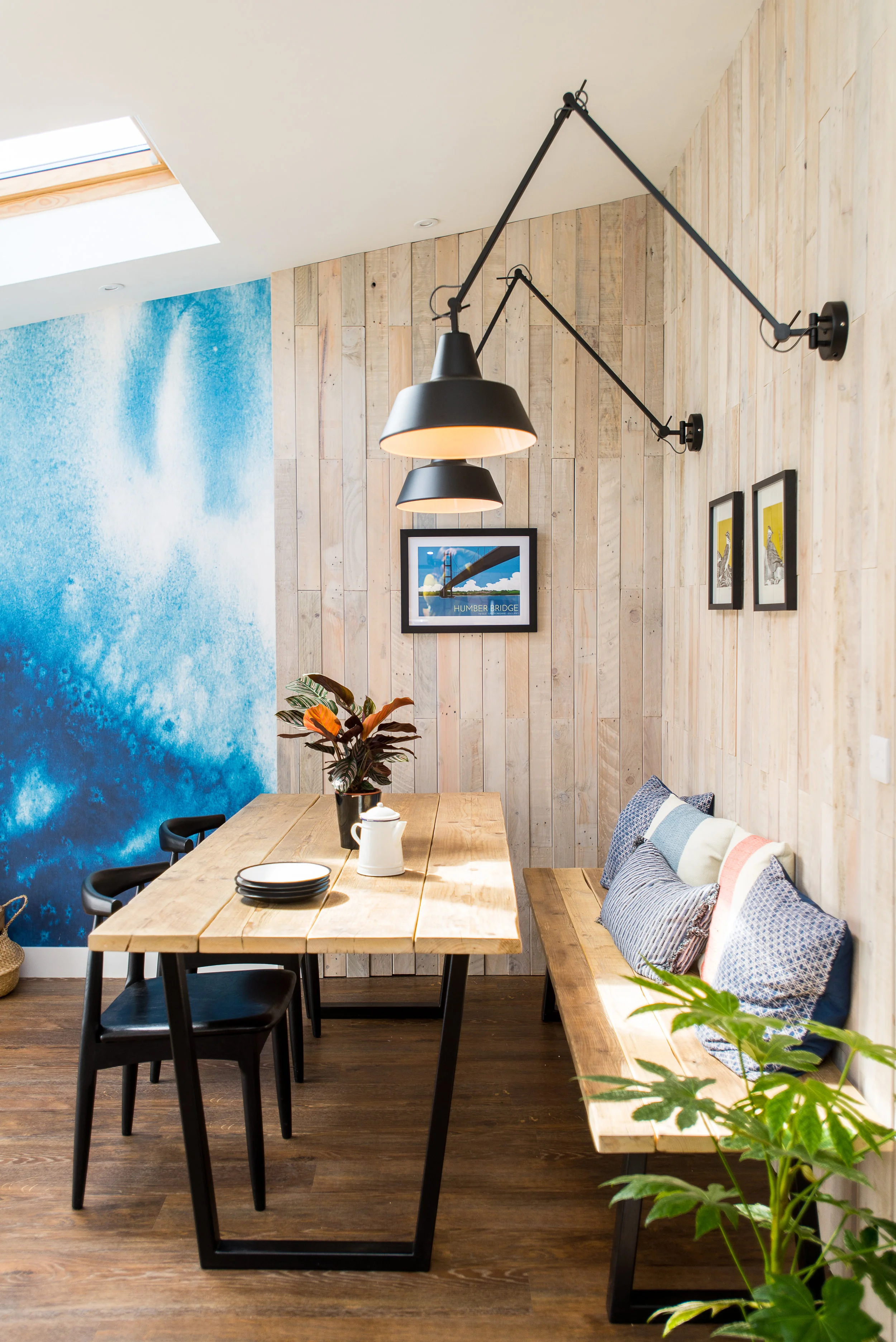 Industrial dining area with timber cladding and black angle wall lights