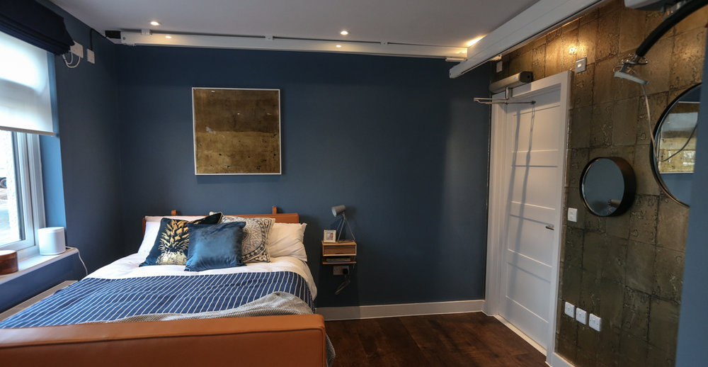 Blue coloured bedroom with a hospital bed with a leather headboard and footboard. 