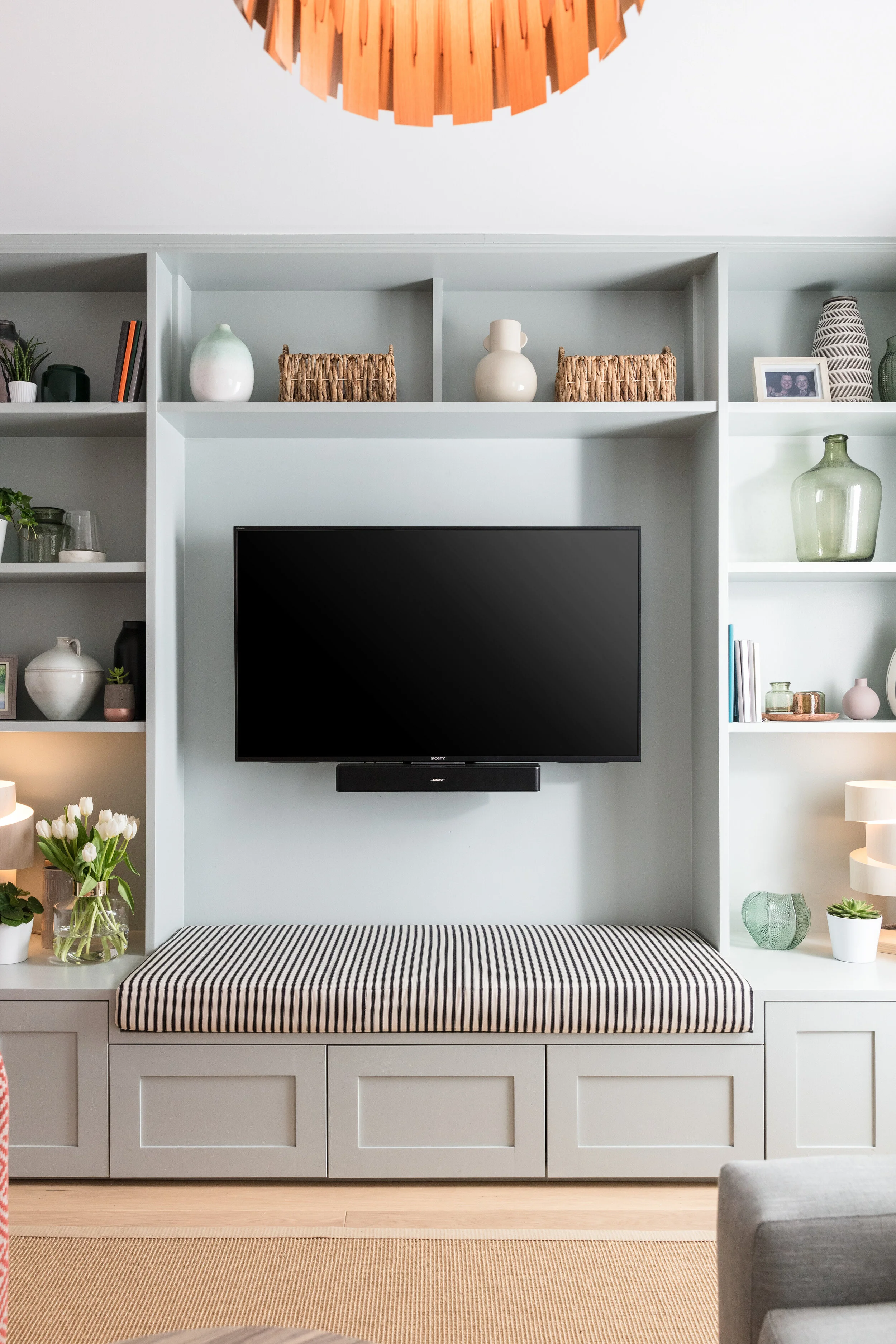 Bespoke built in TV unit with stripy upholstered bench under the TV