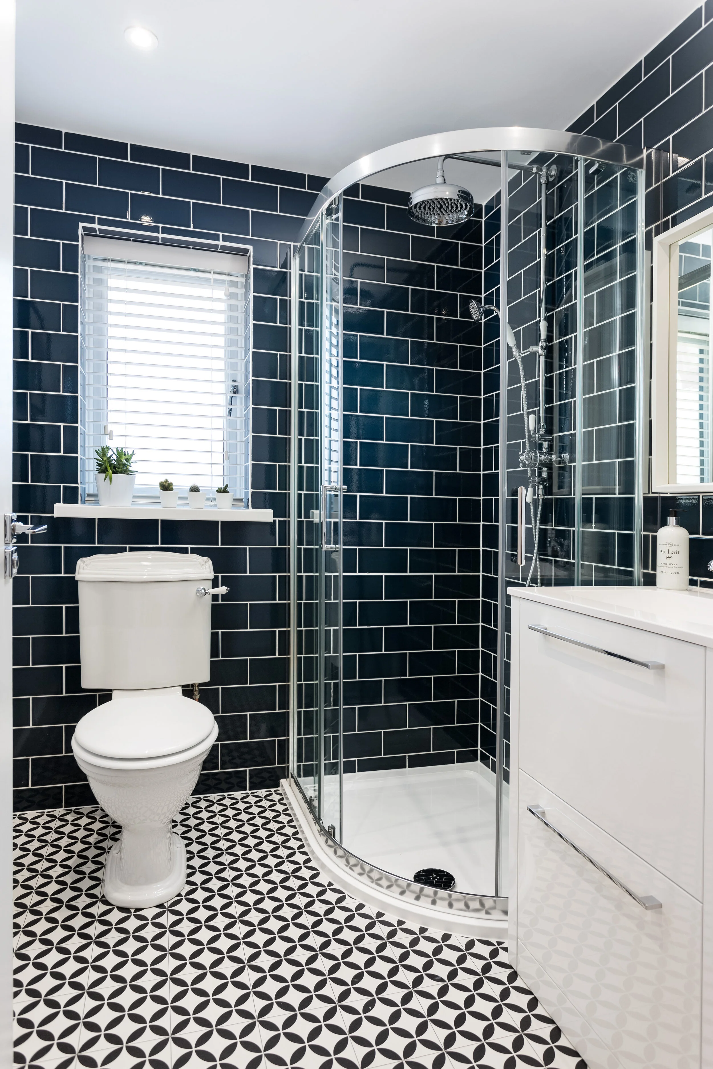 Shower room with dark navy metro tiles and black and white patterned floor