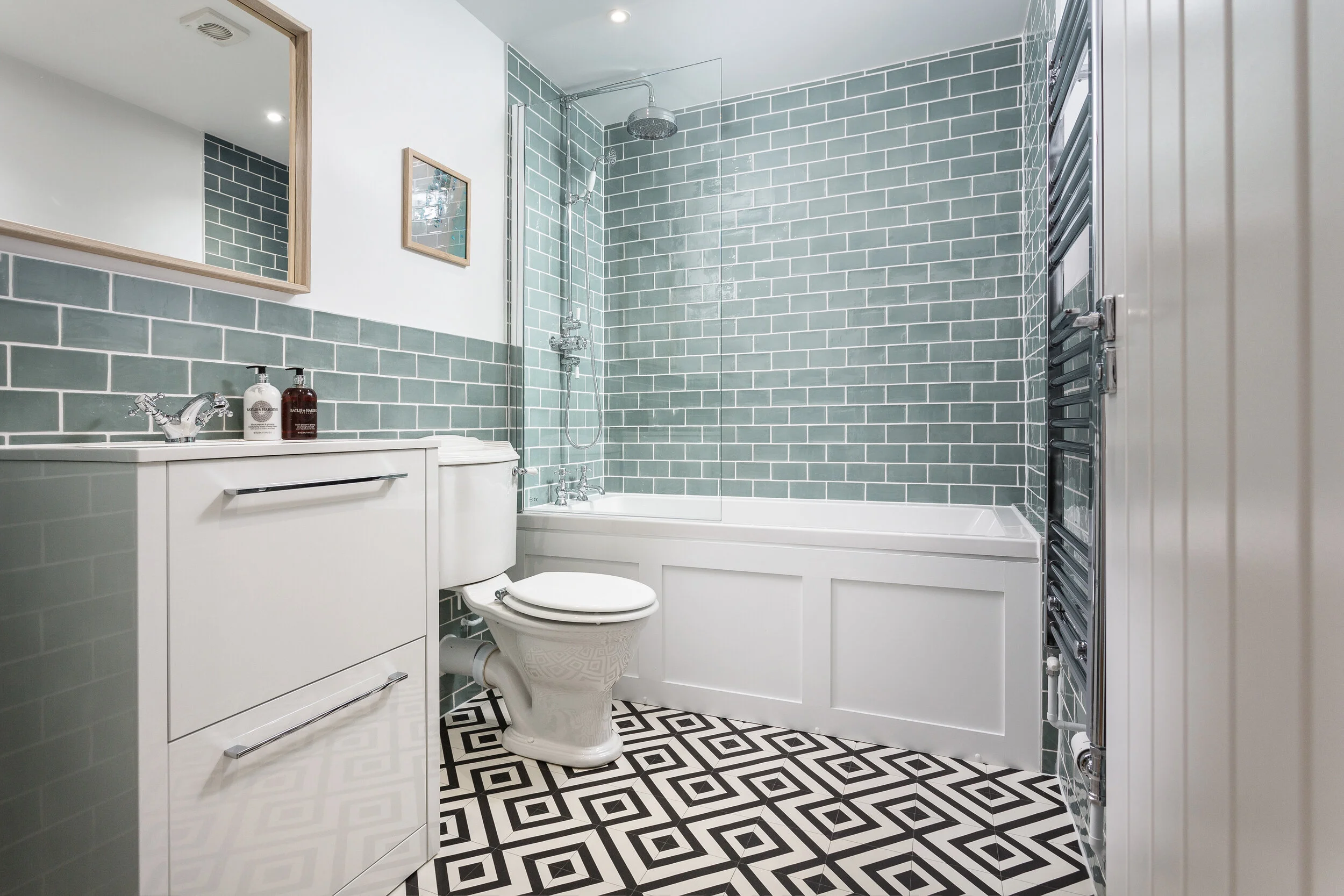 Green bathroom with a shaker style panel, metro tiles and a black and white geometric floor