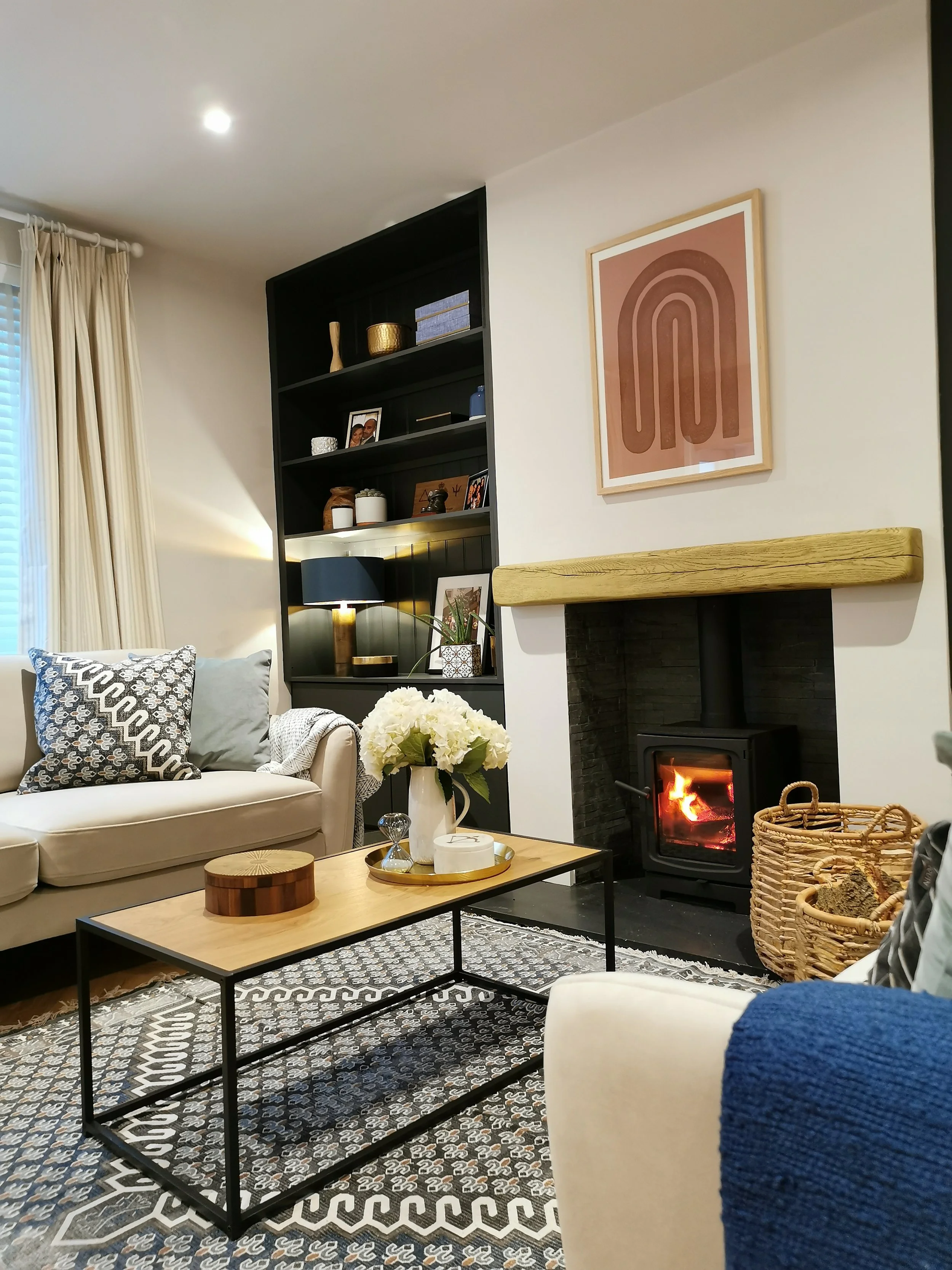 White living room with log burner and black built in shelving on both sides of chimney breast