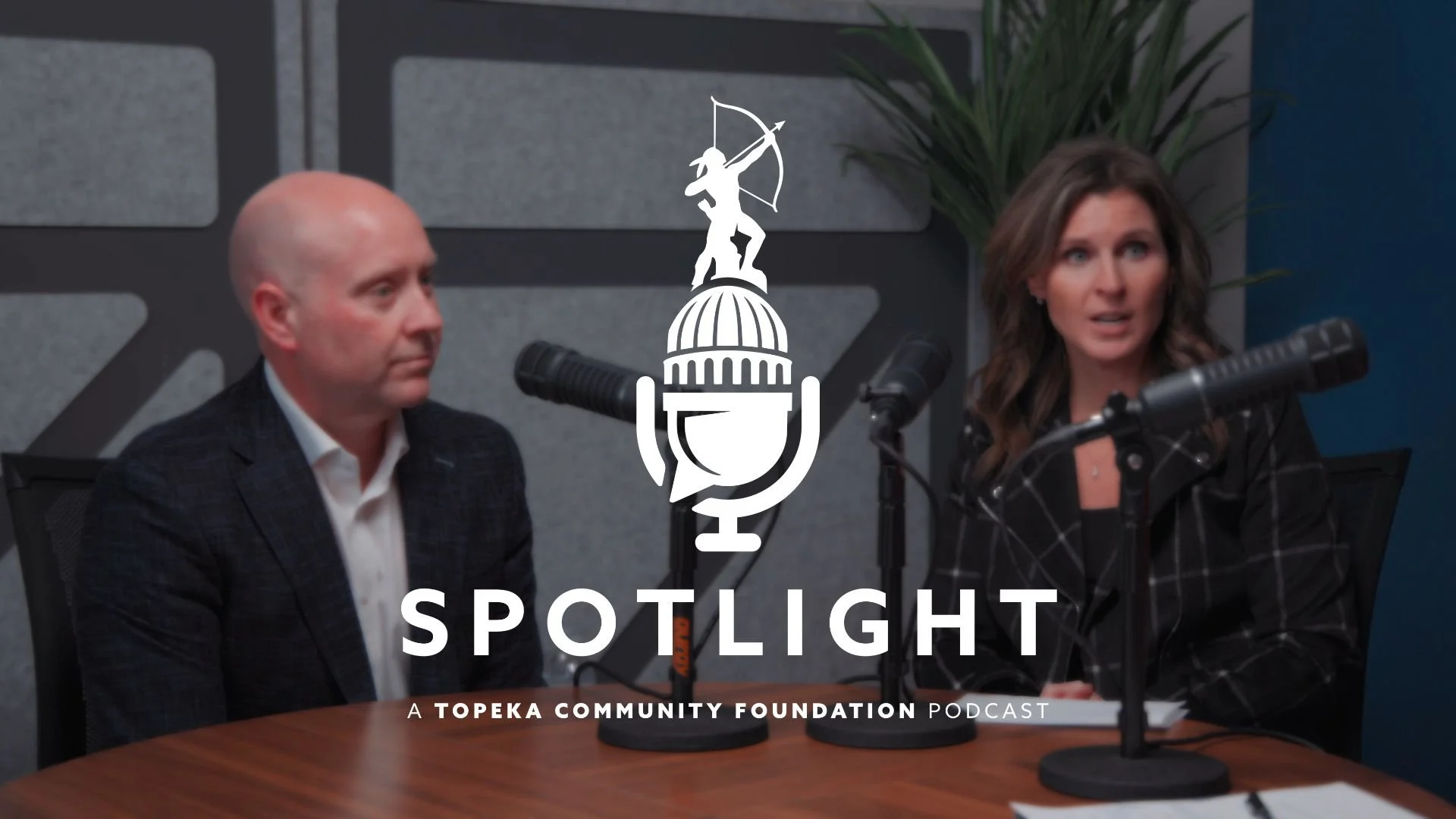 Cody Foster and Carrie Higgins sit at a table with microphones, looking off camera. The Spotlight logo is centered on the photo.