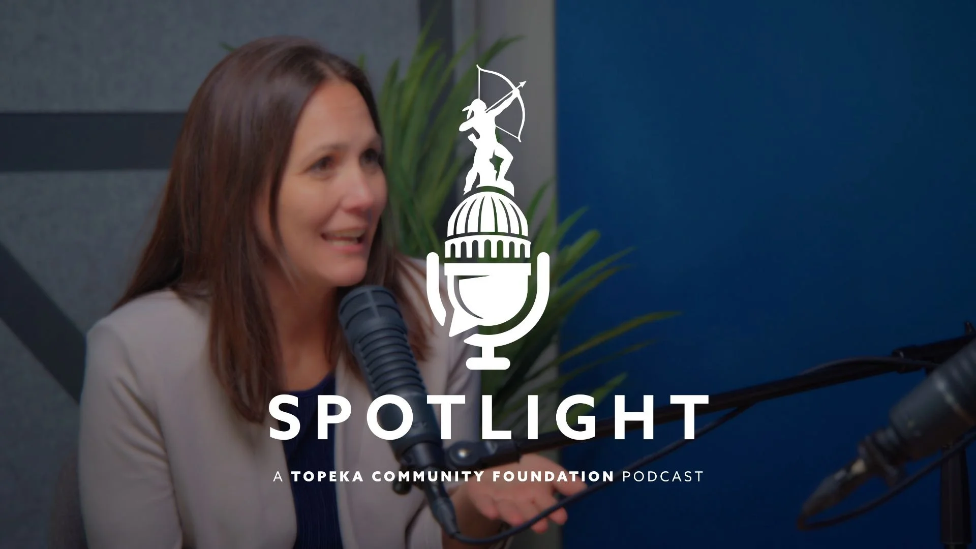 Tara Dimick sits at a table and is speaking into a microphone. The Spotlight podcast logo is centered on the photo.