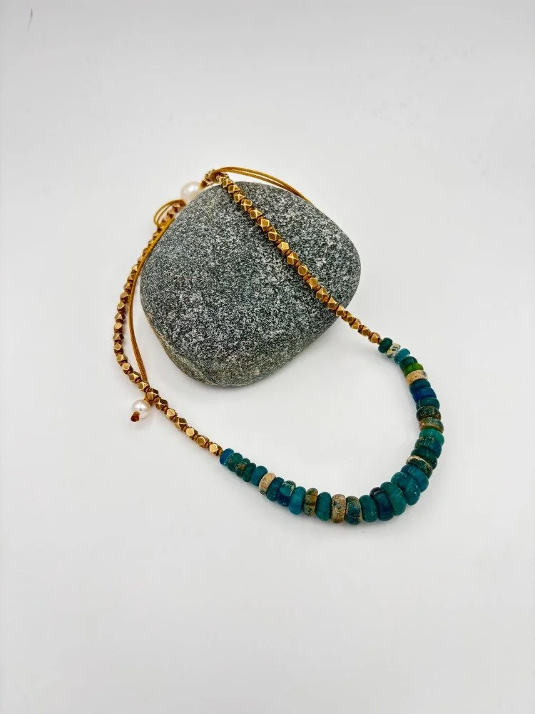 roman glass necklace on grey rock.jpg