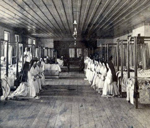 "Old Quebec district - Côte du Palais - Hôtel-Dieu Hospital. Interior view, sick room with the presence of the chaplain and the nuns" (Bibliothèque et Archives nationales du Québec).