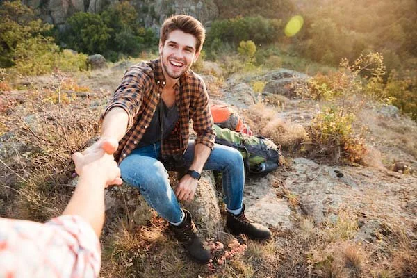 Couples-counseling-young-woman-helps-her-boyfriend-to-get-up-on-their-hiking-journey-600px.jpeg
