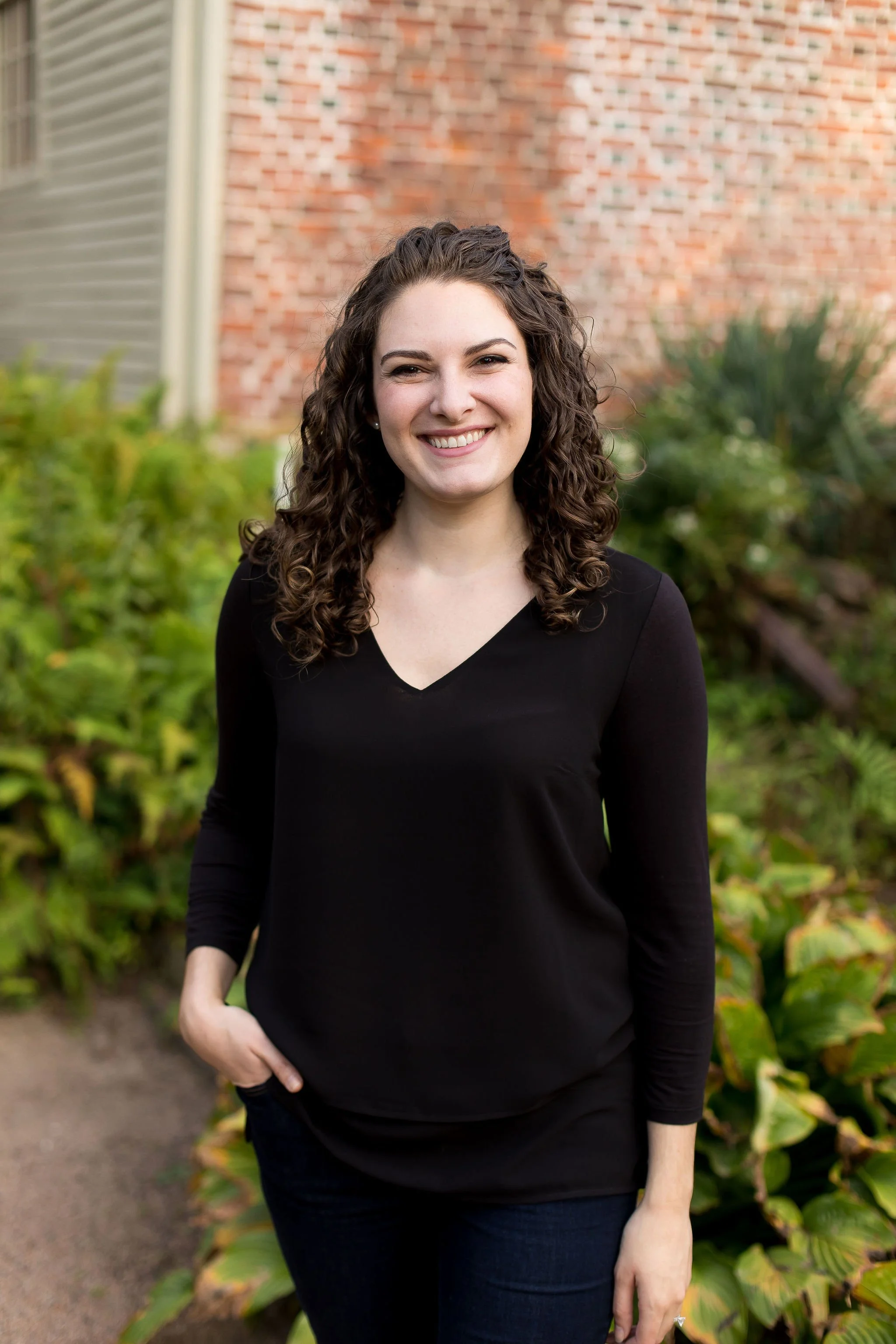 Image of Brittany Schnurr, LMFT therapist in Fairfax and serving women across Virginia and Connecticut, standing outside by a charming historic brick building with a warm and approachable smile.