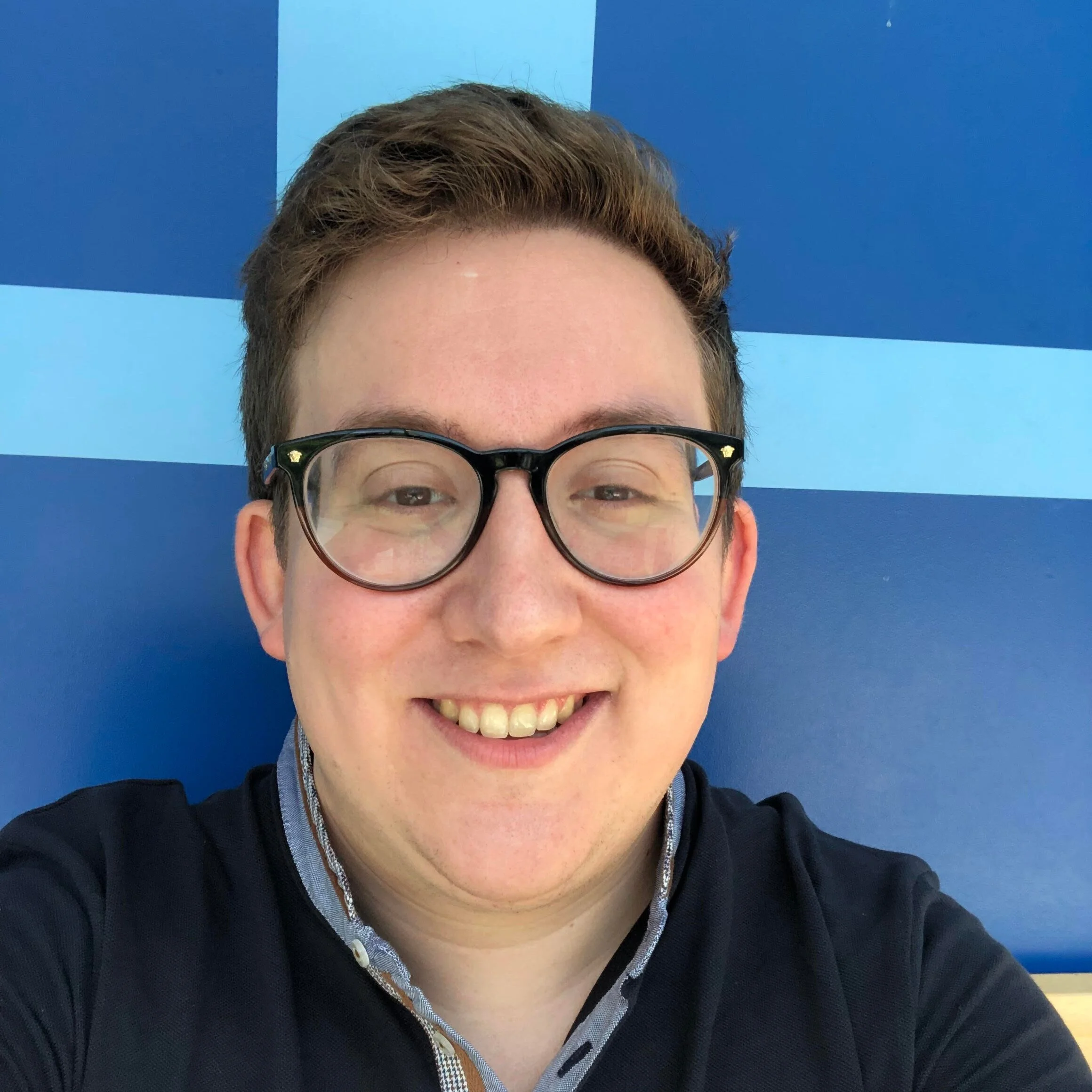 Daniel Etcovitch, a white man with short light brown hair, smiles at you. He is wearing glasses and layered blue shirts.