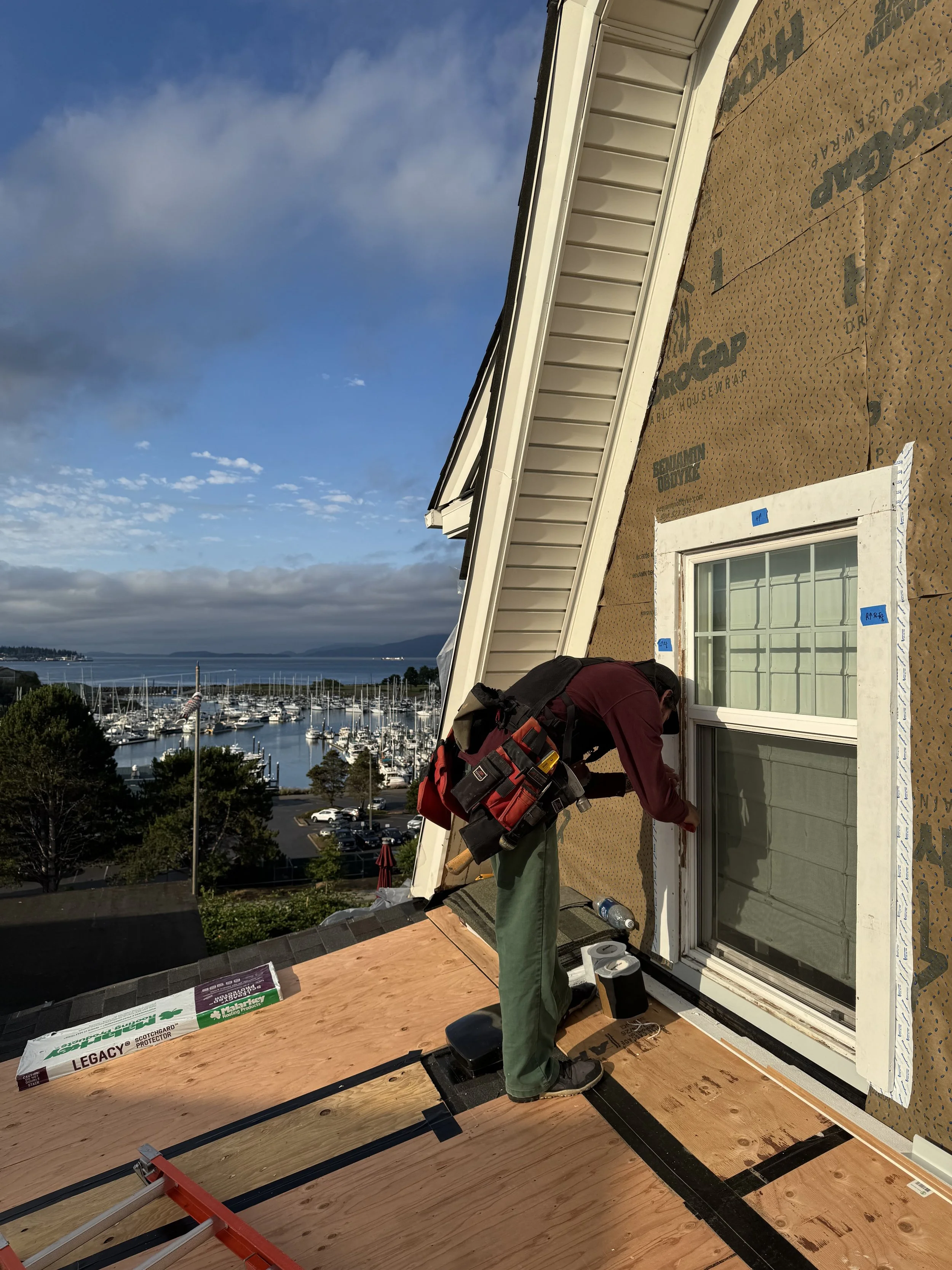 A man waterproofing a window with a view of the marina in the background