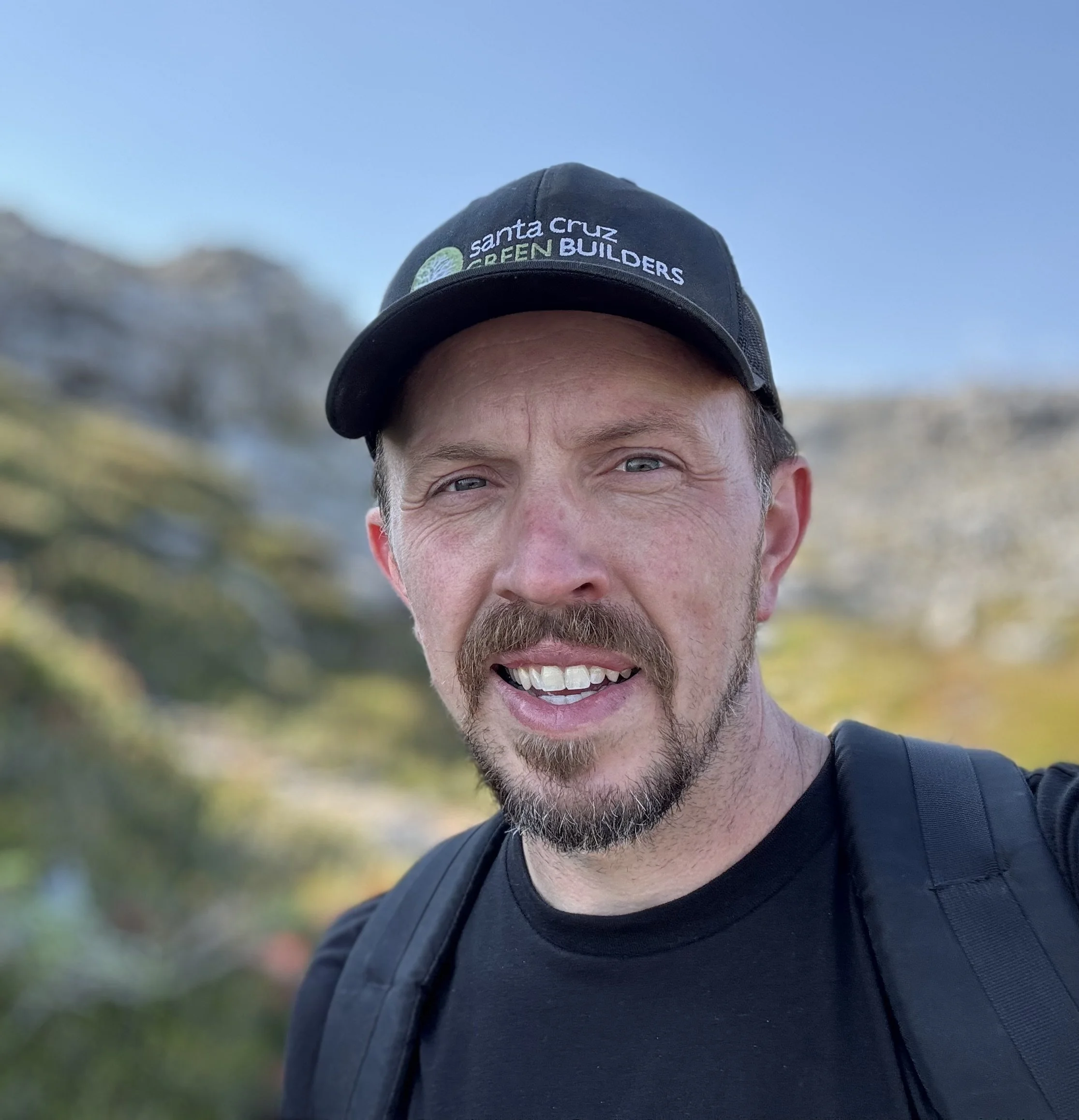 Ian Butler, the owner, hiking in Santa Cruz while wearing a "Green Builders" hat