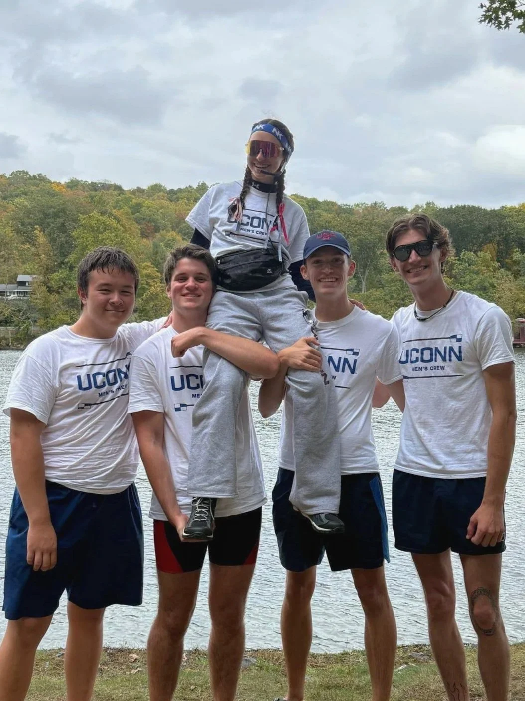 4 athletes holding their Coxswain on shoulders.