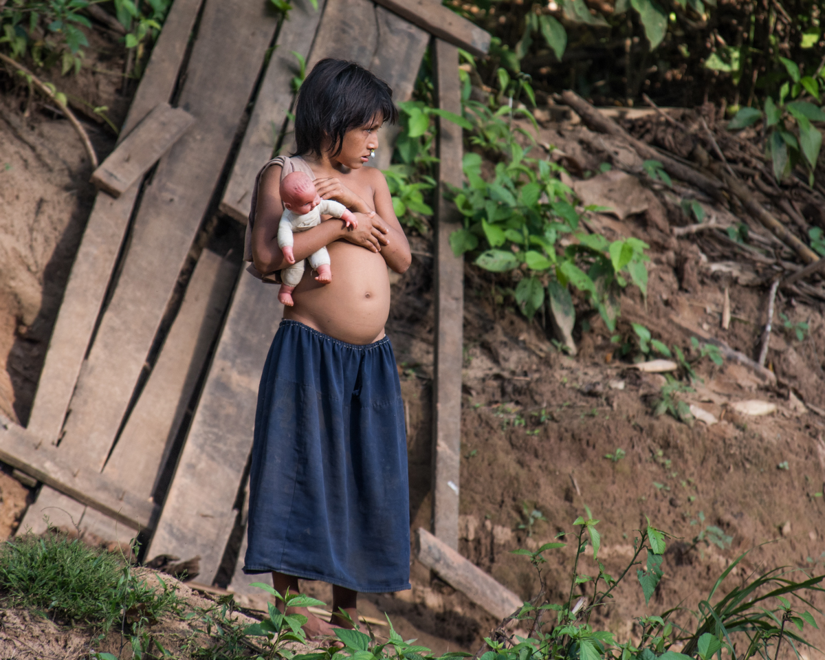 A young girl from Caocatl inquisitively stands on the shore of Río Fierro with a modern doll. The girl shows signs of parasitic pestilence that often accompanies nomadic communities as they are forced to become sedentary and water supplies are easily contaminated. Efforts to provide clean water and health posts have been extremely successful in lowering parasitic related deaths, but due to the immensity of Manu, some Matsigenka communities, like this one, have been overlooked. April 21, 2016.