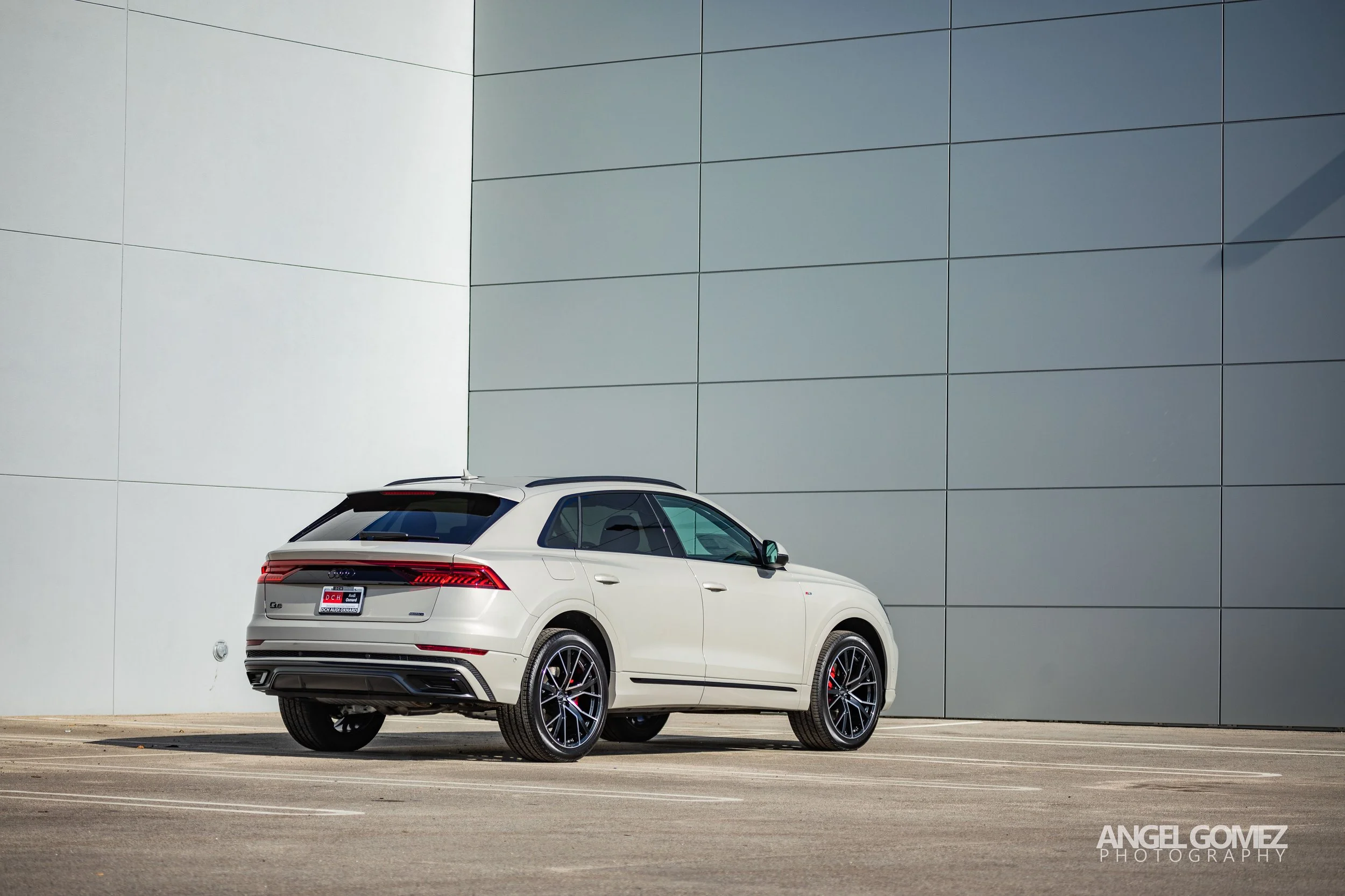 White luxury SUV parked next to a modern gray wall.