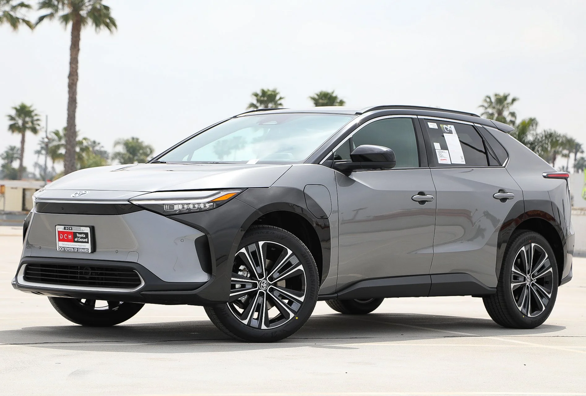 Gray Toyota electric SUV parked in an outdoor lot with palm trees in the background.