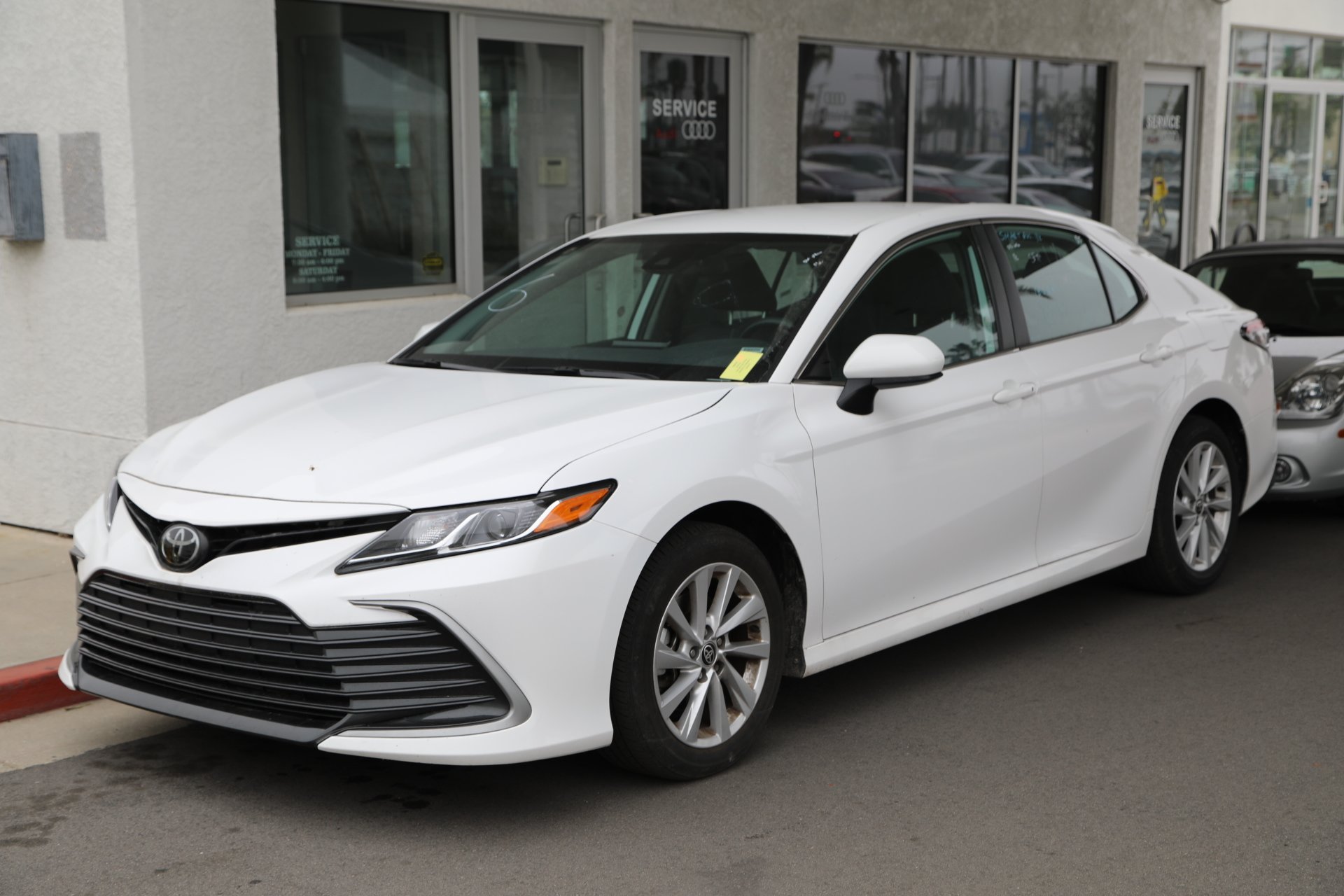 White Toyota Camry parked outside an Audi service center
