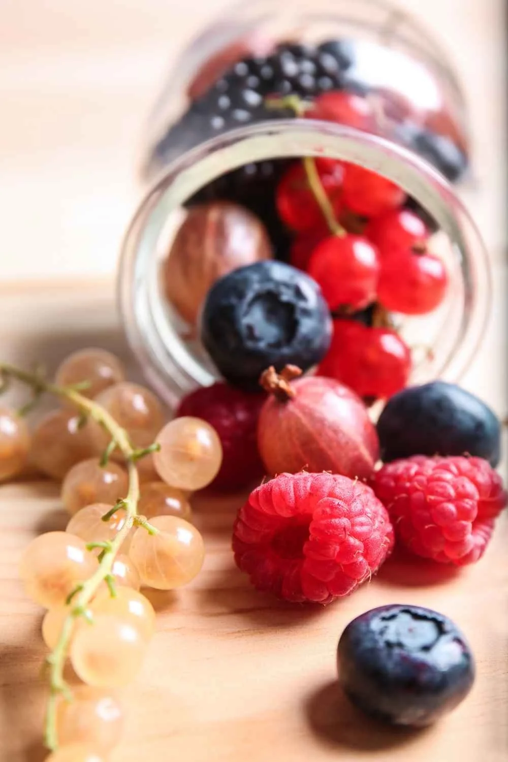 food waste, berries rolling out of a glass jar
