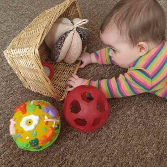 natural baby rubber balls in a basket being played with by a baby