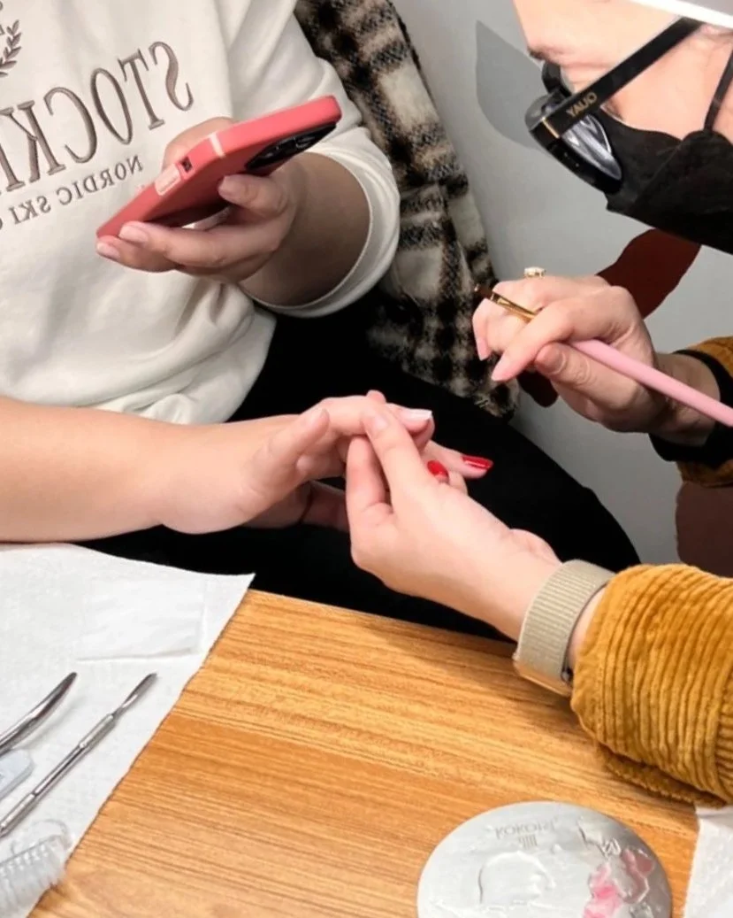Hands-on nail education with students working together during a professional certification workshop.
