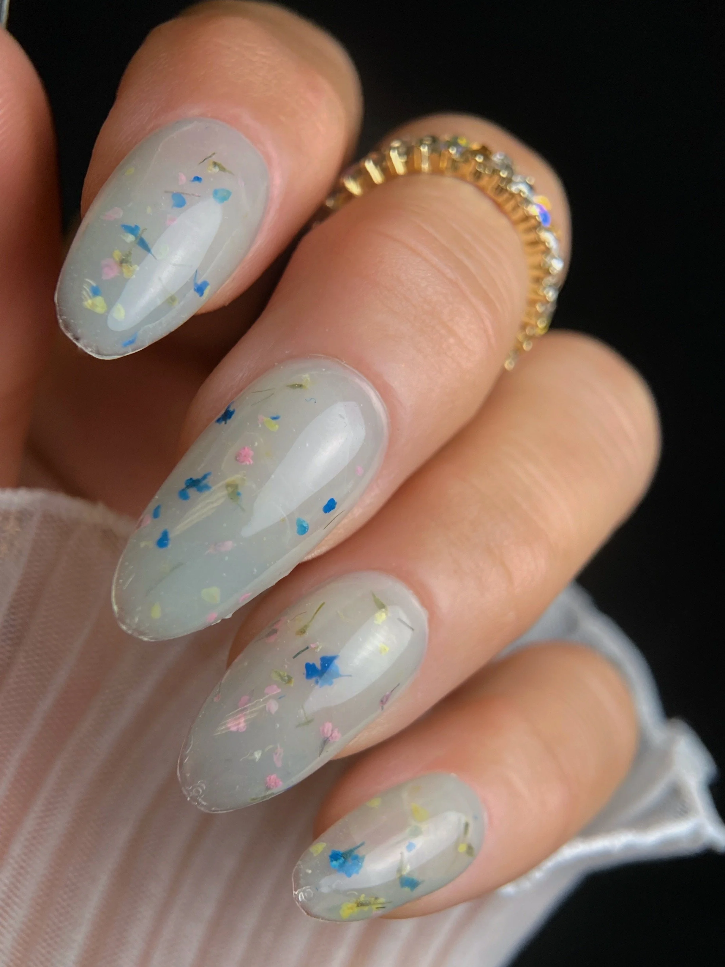 KOKOIST Botanical Flower Gel BF-02 Milky Green swatch with colorful dried flowers and botanical pieces in a translucent milky green base.