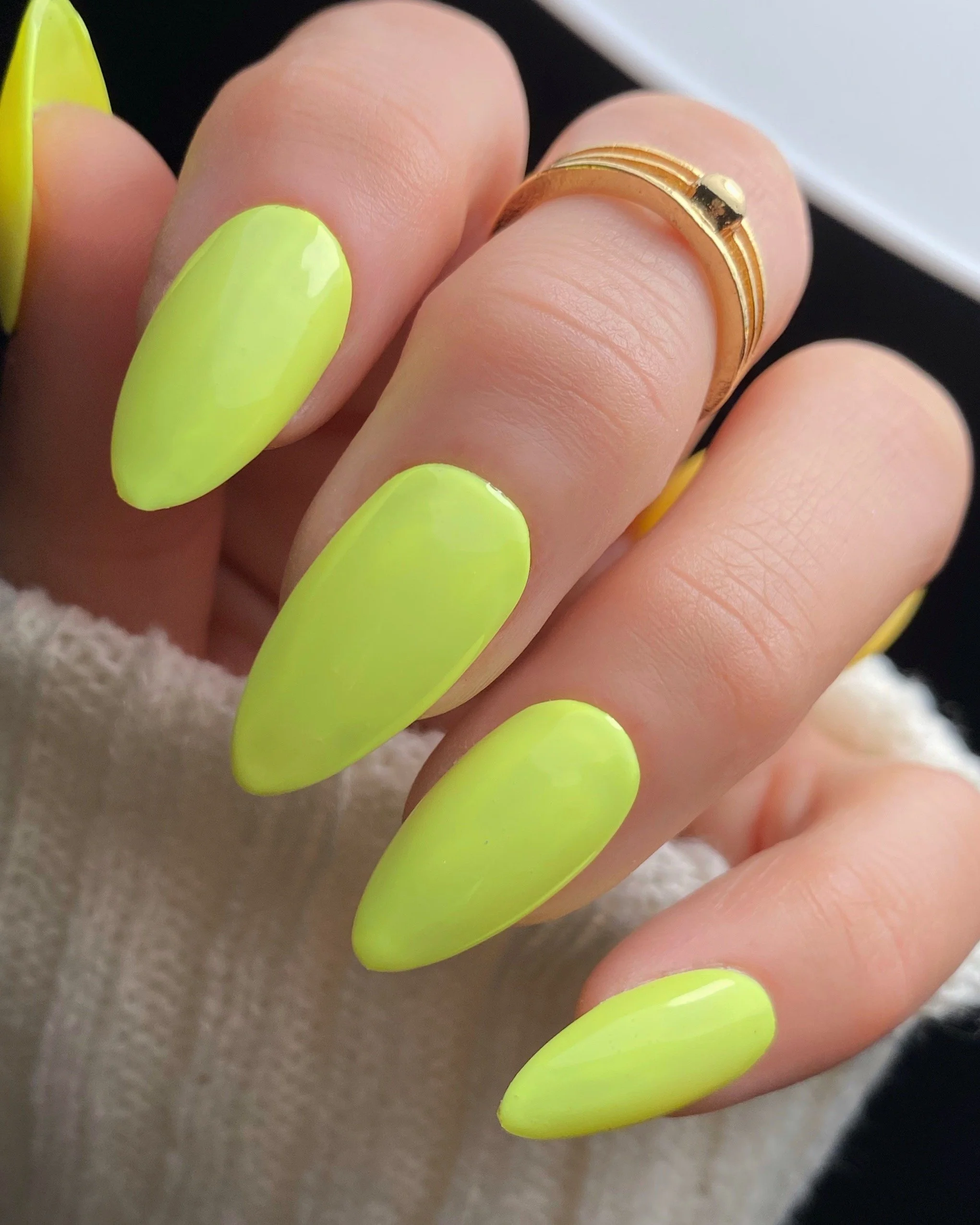 Nail Thoughts Celebration Collection gel color swatch in shade "Wait We Need A Pic" bright yellow on manicured hand with rings and knit sleeve