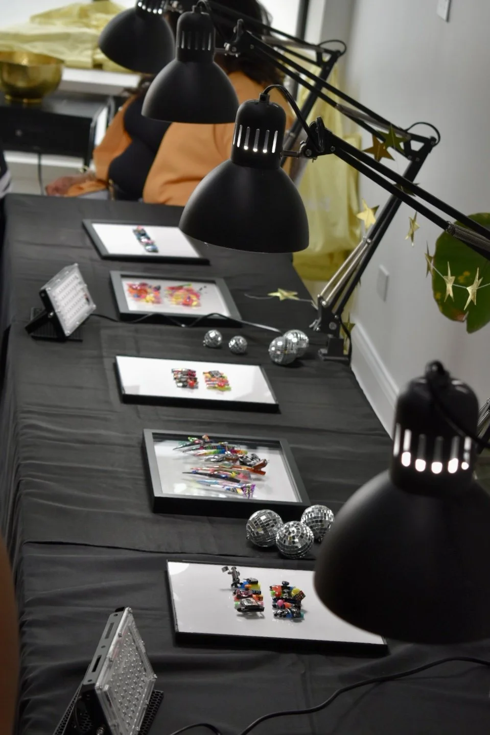 Display of Totally '80s nail art competition entries at The Mani Mixer 2026 featuring framed nail art displays, task lamps, disco ball decorations, and judging stations.