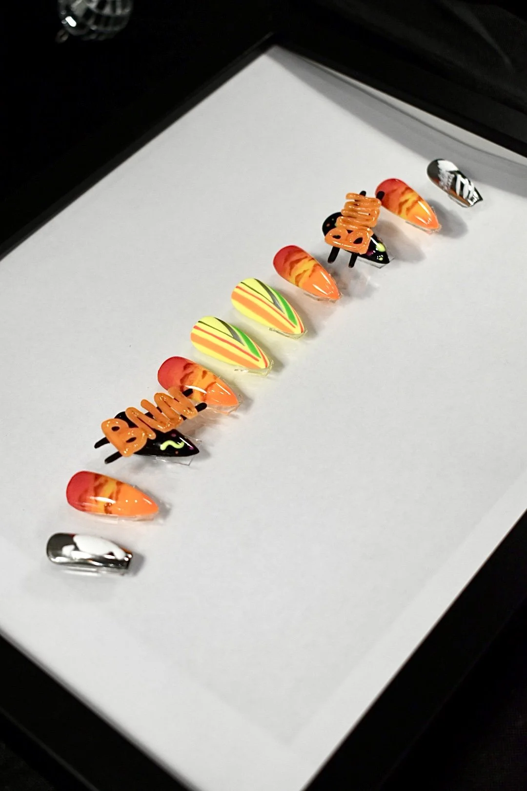 Totally '80s nail art competition entry at The Mani Mixer 2026 featuring chrome accents, neon gradients, tiger stripes, and sculptural "BNN" lettering.