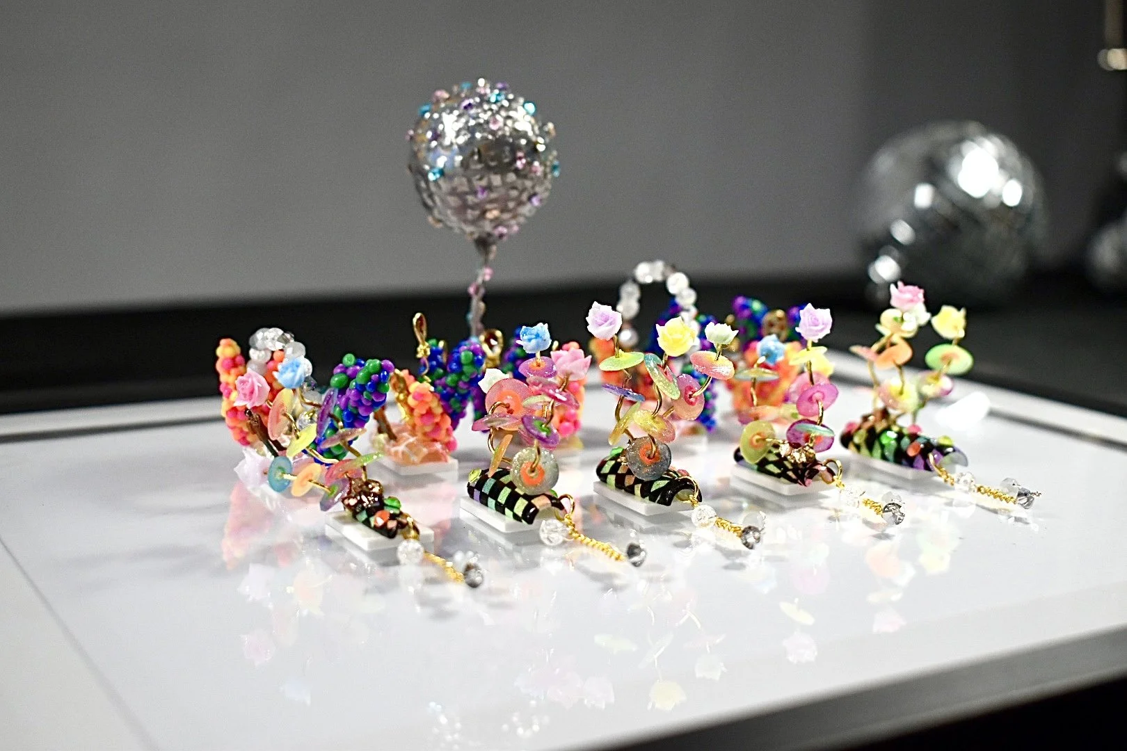Totally '80s nail art competition entry at The Mani Mixer 2026 featuring miniature elements, colorful flowers, balloon clusters, beaded details, and a disco ball centerpiece.