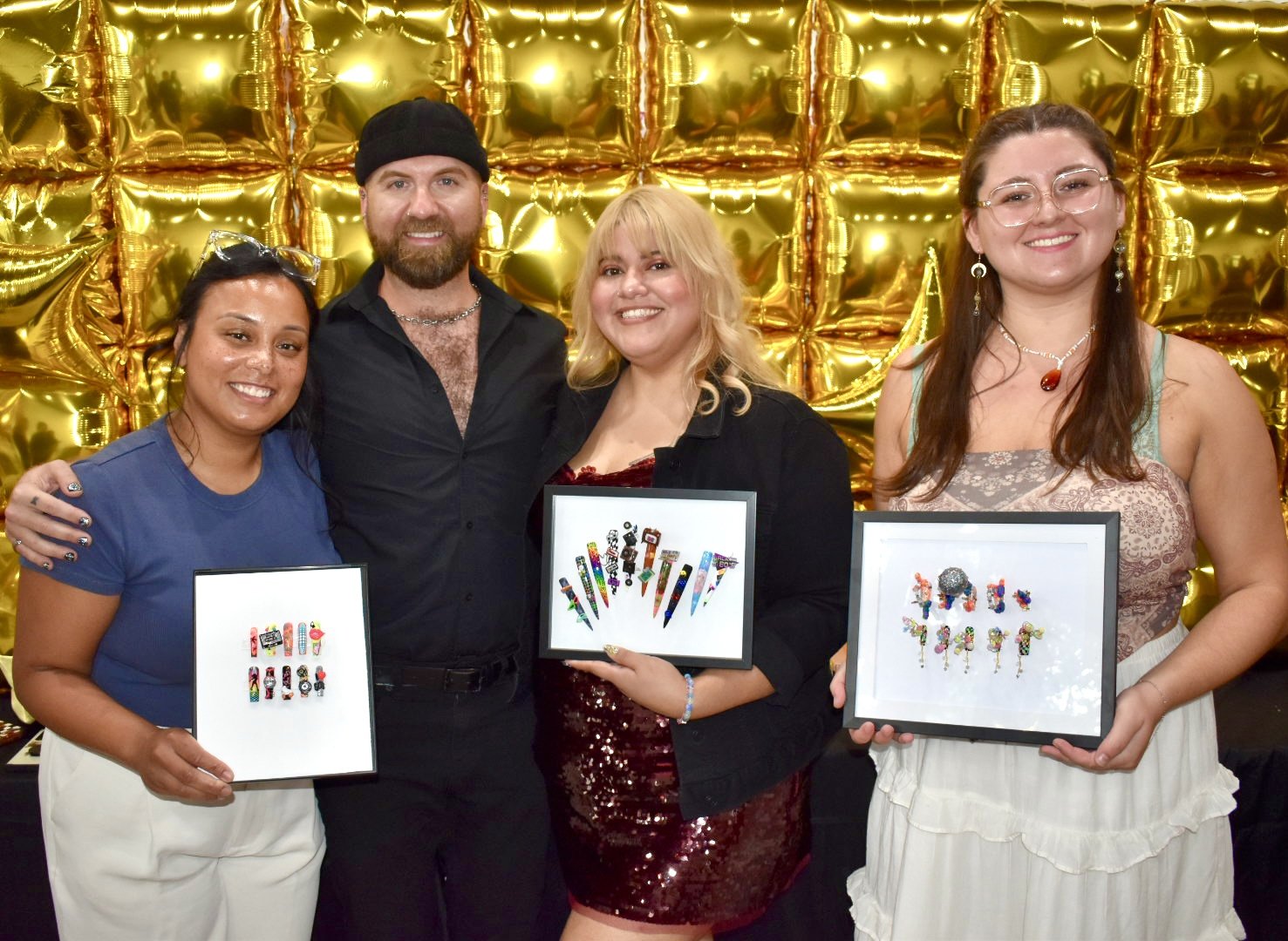 Winners of the Totally '80s nail art competition at The Mani Mixer 2026 posing with their framed winning nail art entries alongside event host Dylan Pritchard.