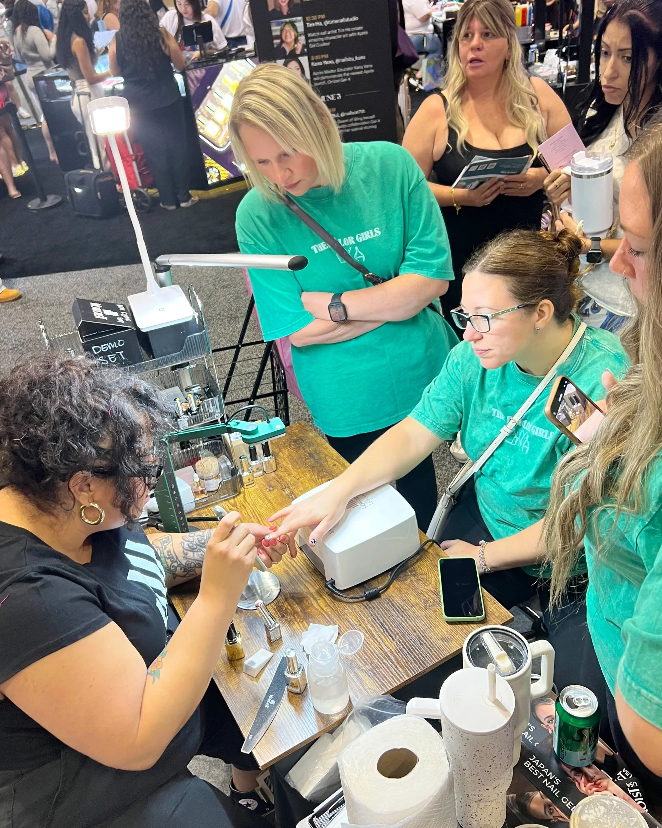 Rachel Messick demonstrating Kokoist gel nail techniques for attendees at a professional beauty trade show.
