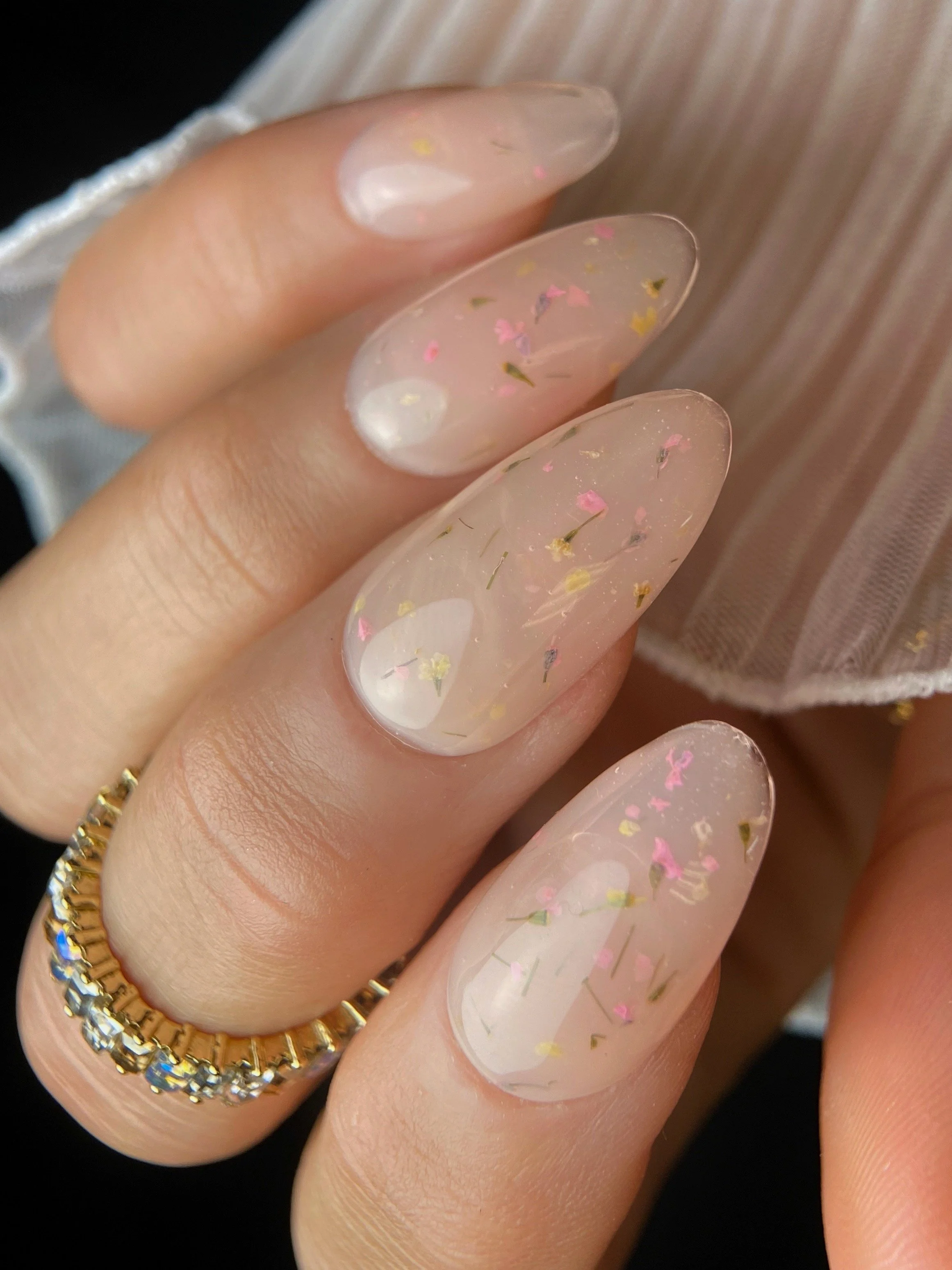 KOKOIST Botanical Flower Gel BF-04 Milky Peach swatch with pink and yellow dried flower pieces in a translucent milky peach base.