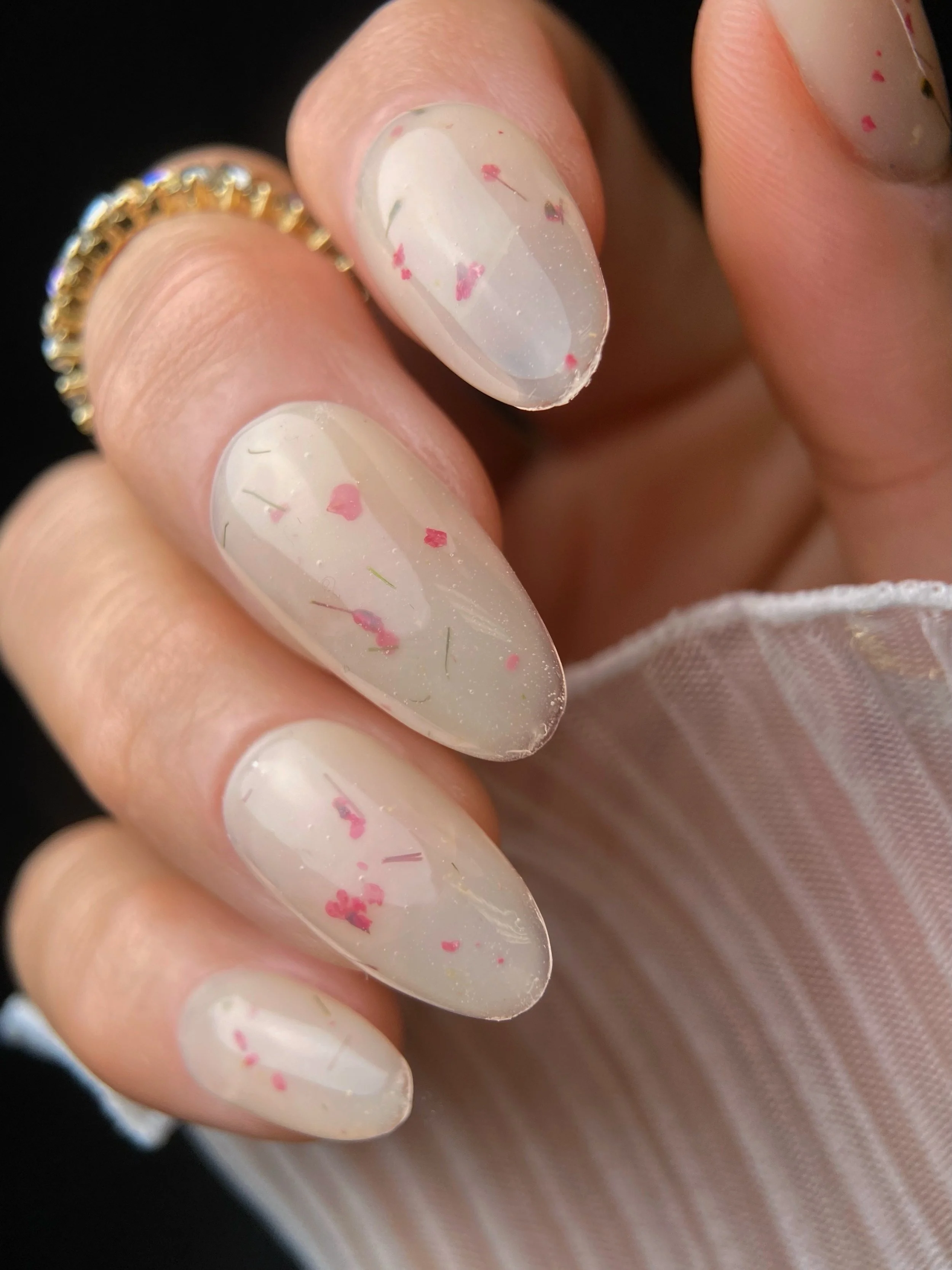 KOKOIST Botanical Flower Gel BF-06 Milky Beige swatch with pink dried flowers and fine botanical pieces in a translucent milky beige base.
