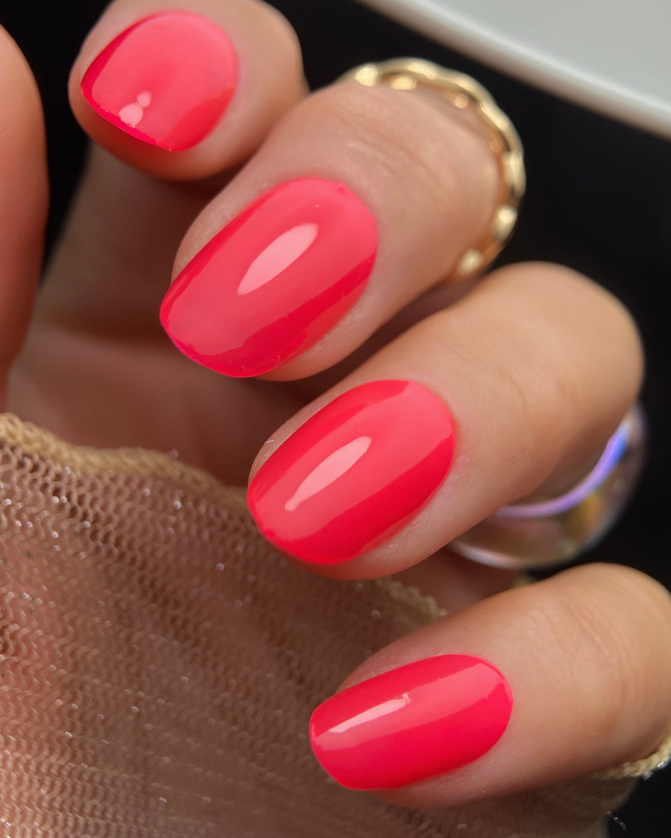 Close-up swatch of Orly Hibis-Kiss neon coral nail polish on oval shaped nails.