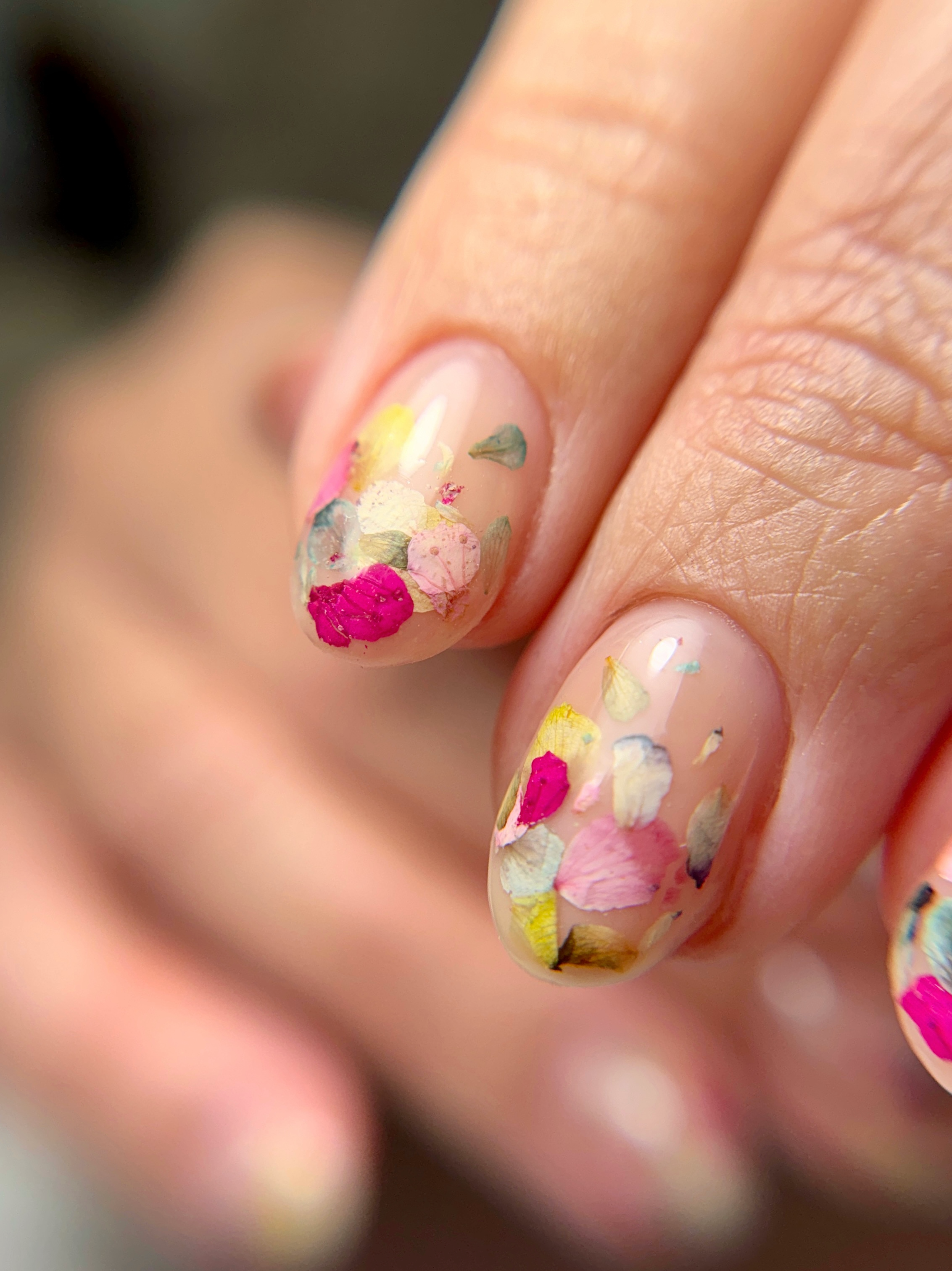 Structured gel manicure with colorful flower petals embedded beneath a glossy finish.