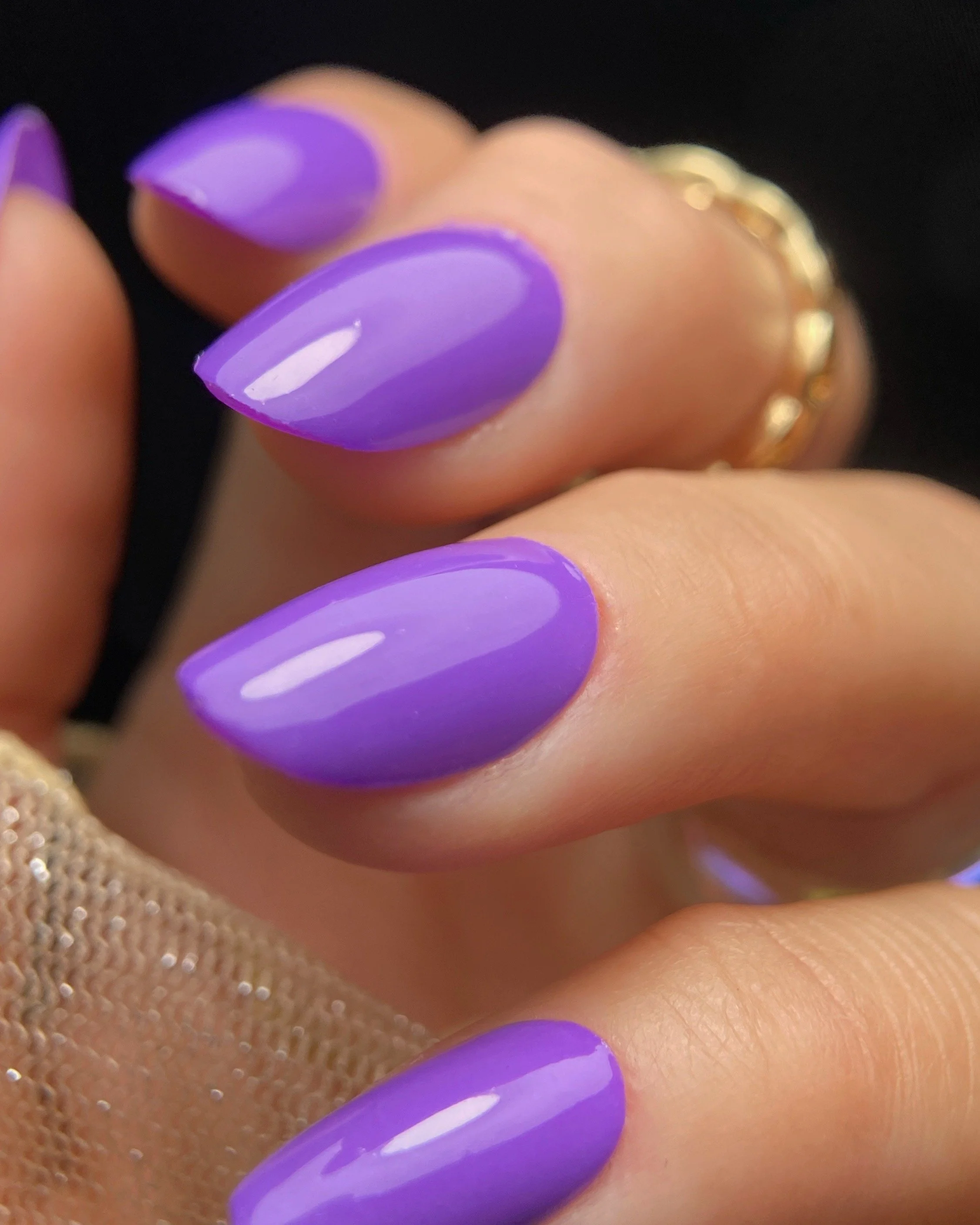Close-up swatch of Orly Rave Wave electric purple nail polish on almond shaped nails.
