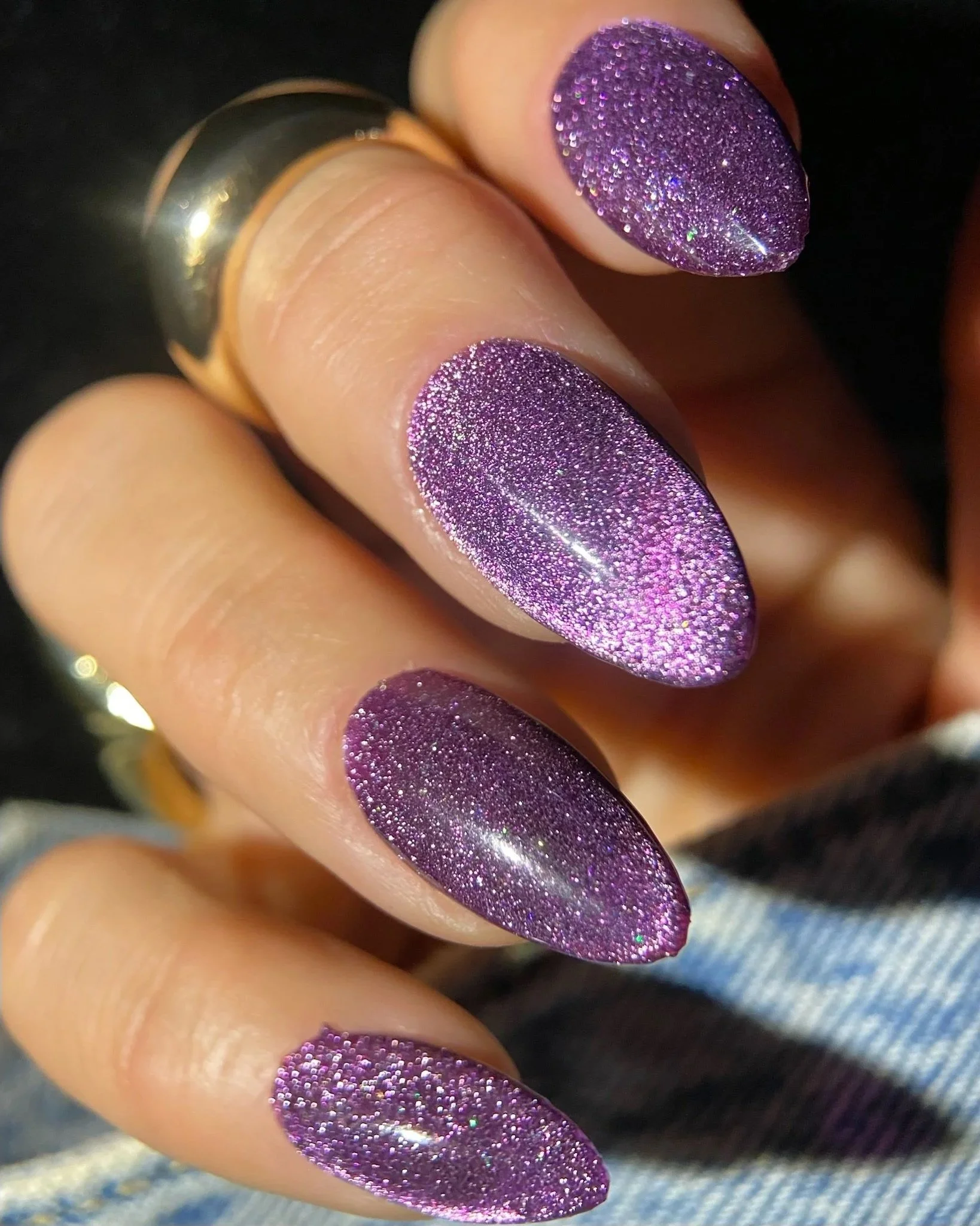Hand with glittery purple cat-eye nails.