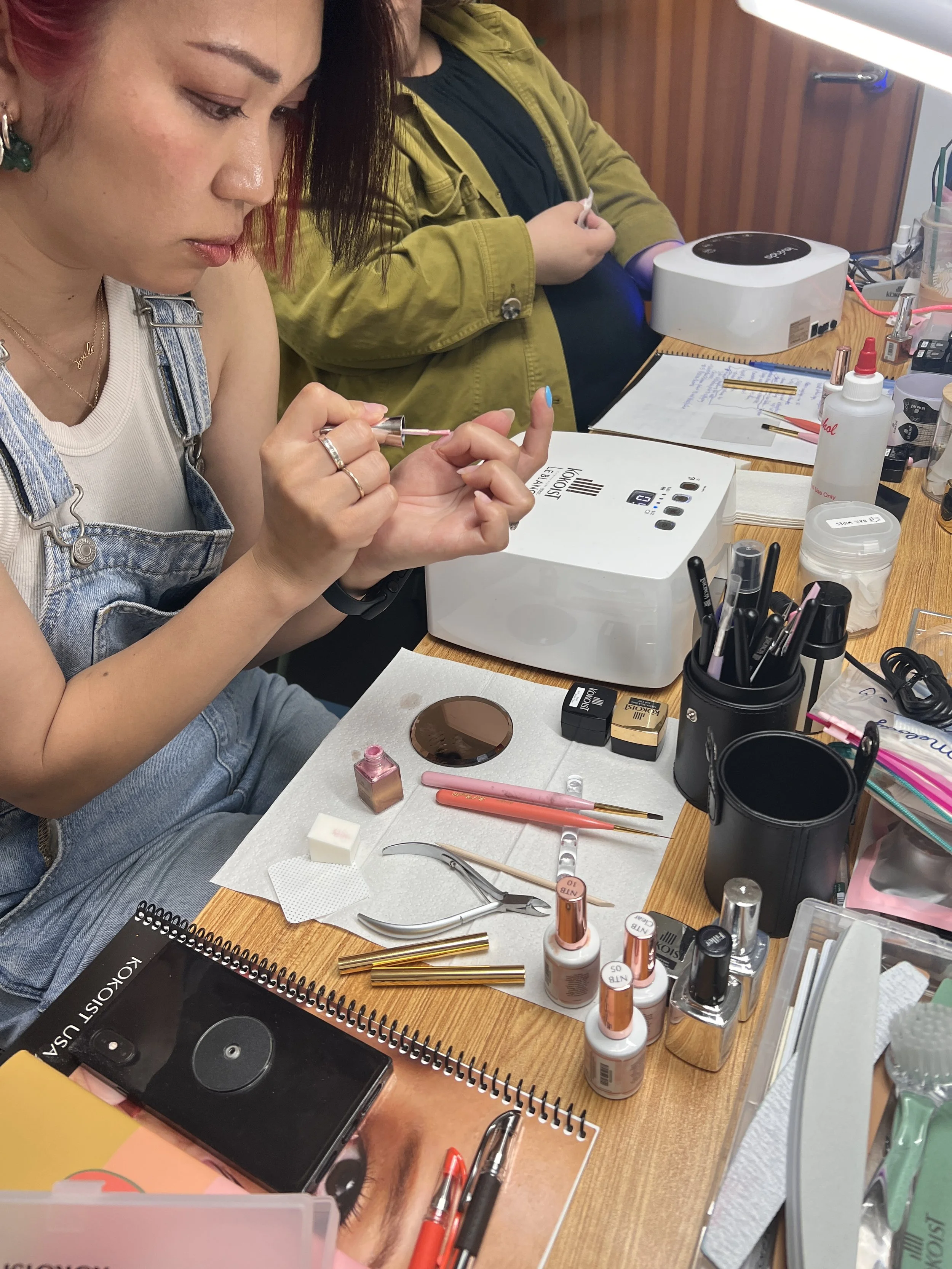 Student practicing gel nail application techniques during a professional certification class.