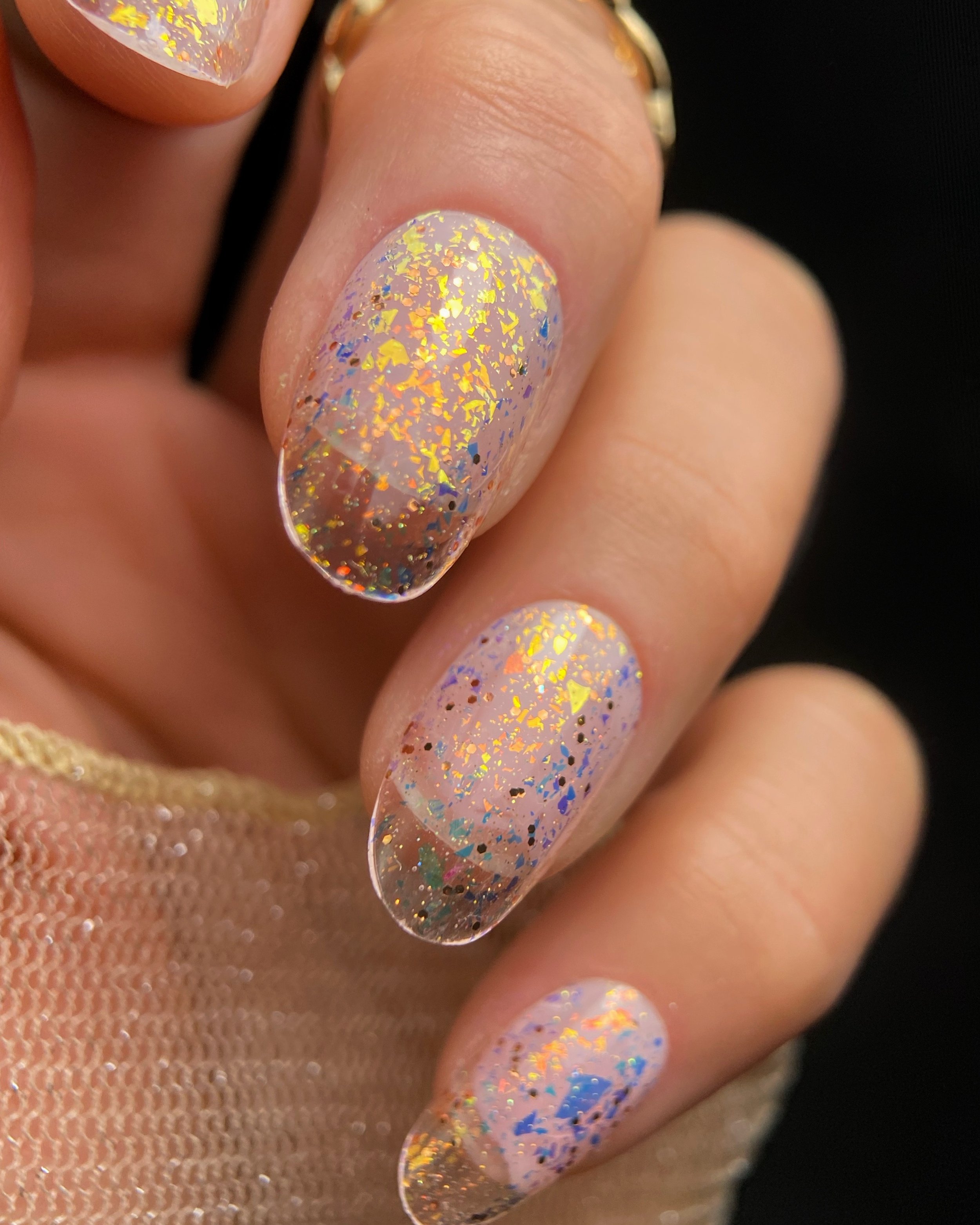 Close-up swatch of Orly Golden Hour glitter topper on oval shaped nails featuring copper, gold, and blue color-shifting flakes.