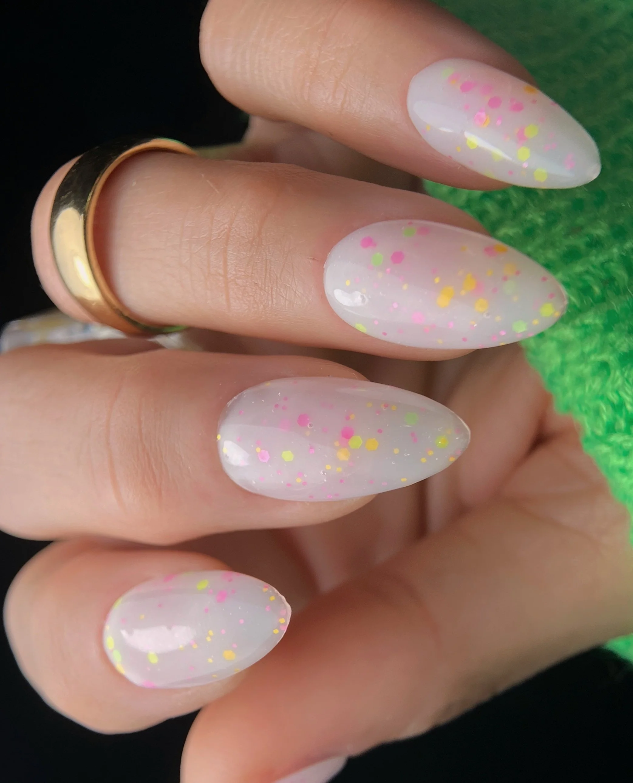 Nail Thoughts Celebration Collection gel color swatch in shade "Ice Cream Sundae" milky white with bright satin confetti glitter on maicured hand with rings and knit sleeve.