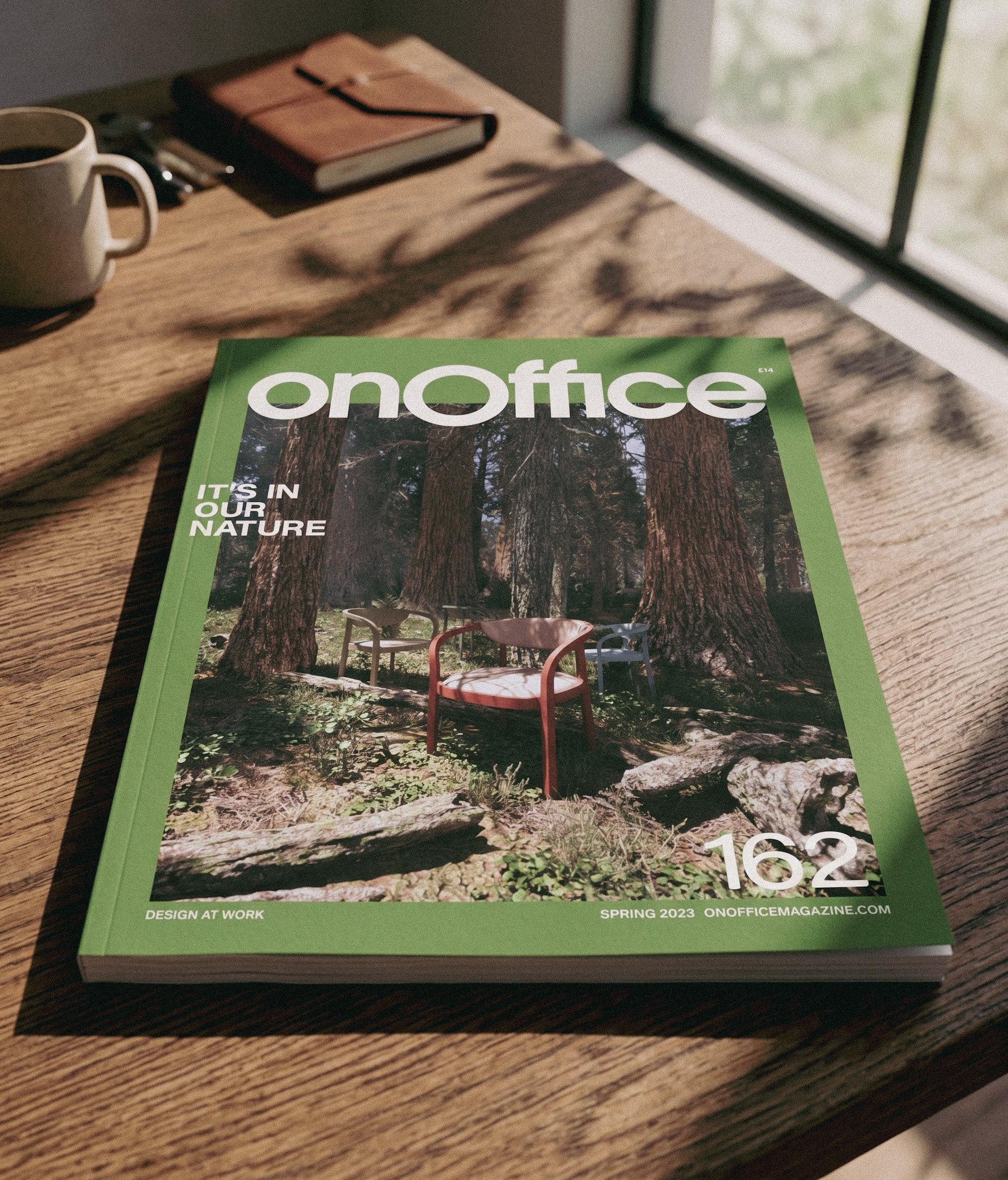 A magazine titled ONOffice laying on a wooden table with a coffee mug, a closed notebook, and some pens nearby. Light coming through a window casts shadows on the table.