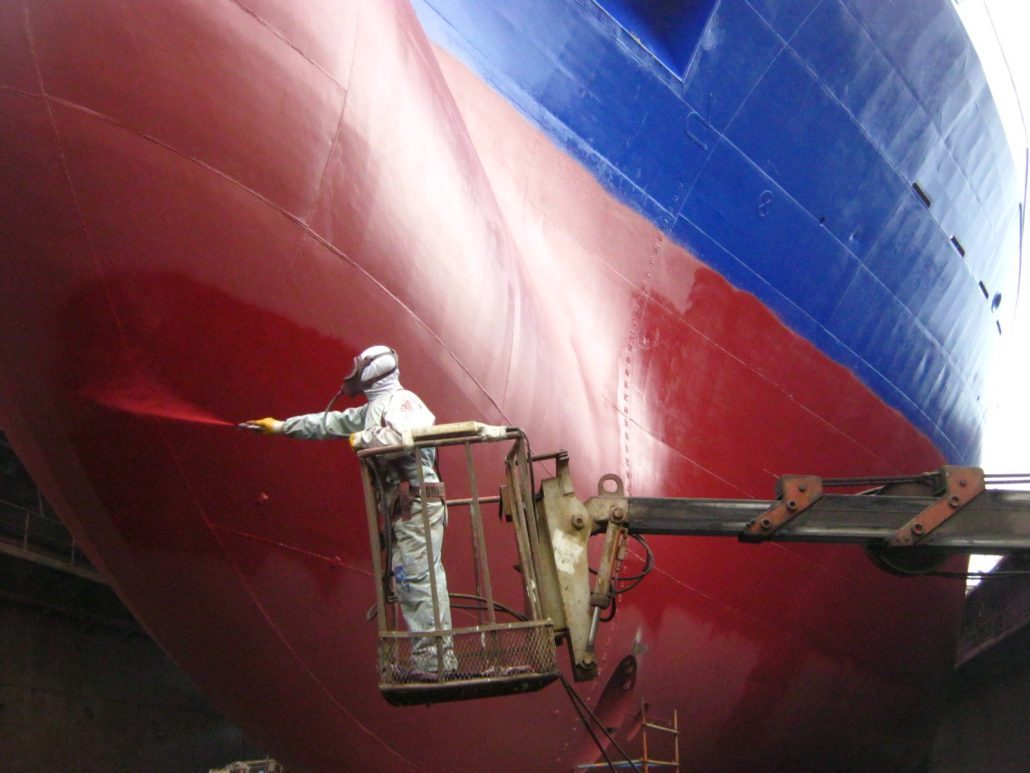 Protecting boat hulls with antifouling paints can lead to lower expenses in fuel. Notice, though, how guarded the painter is in this picture; the toxicity of these paints is nothing to underestimate. Photo credit: coatingpaint.com